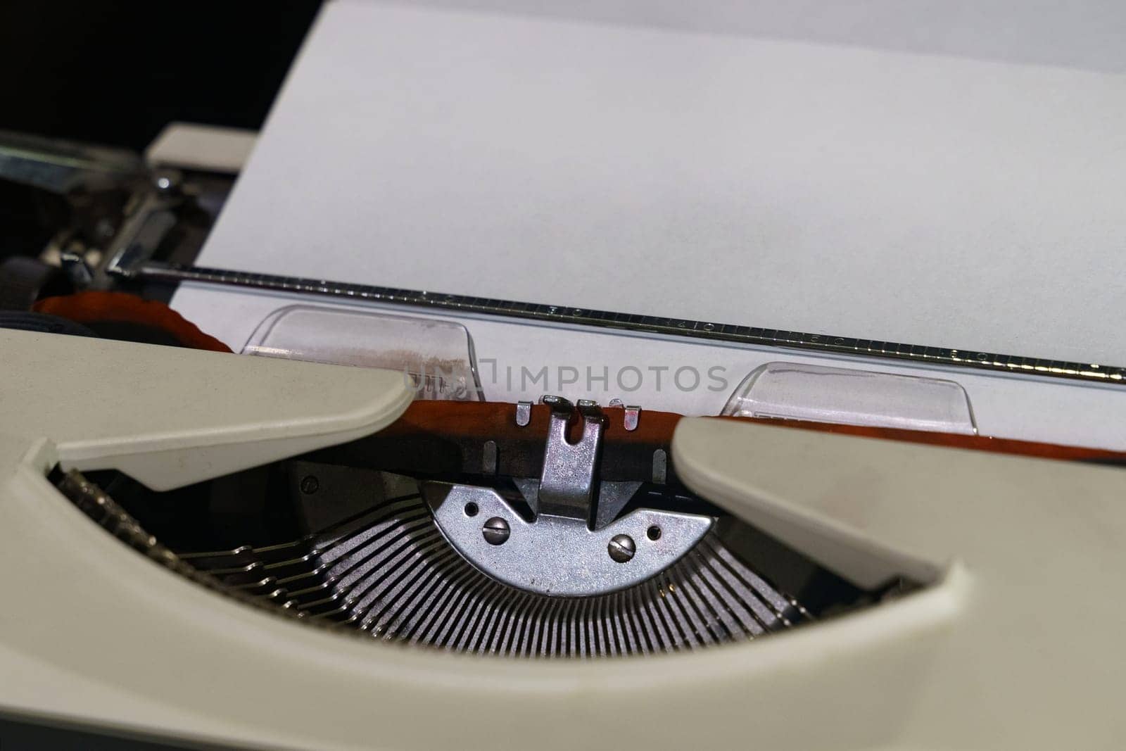 A detailed view of an old-fashioned typewriter with a sheet of paper inserted, showcasing vintage design and functionality.