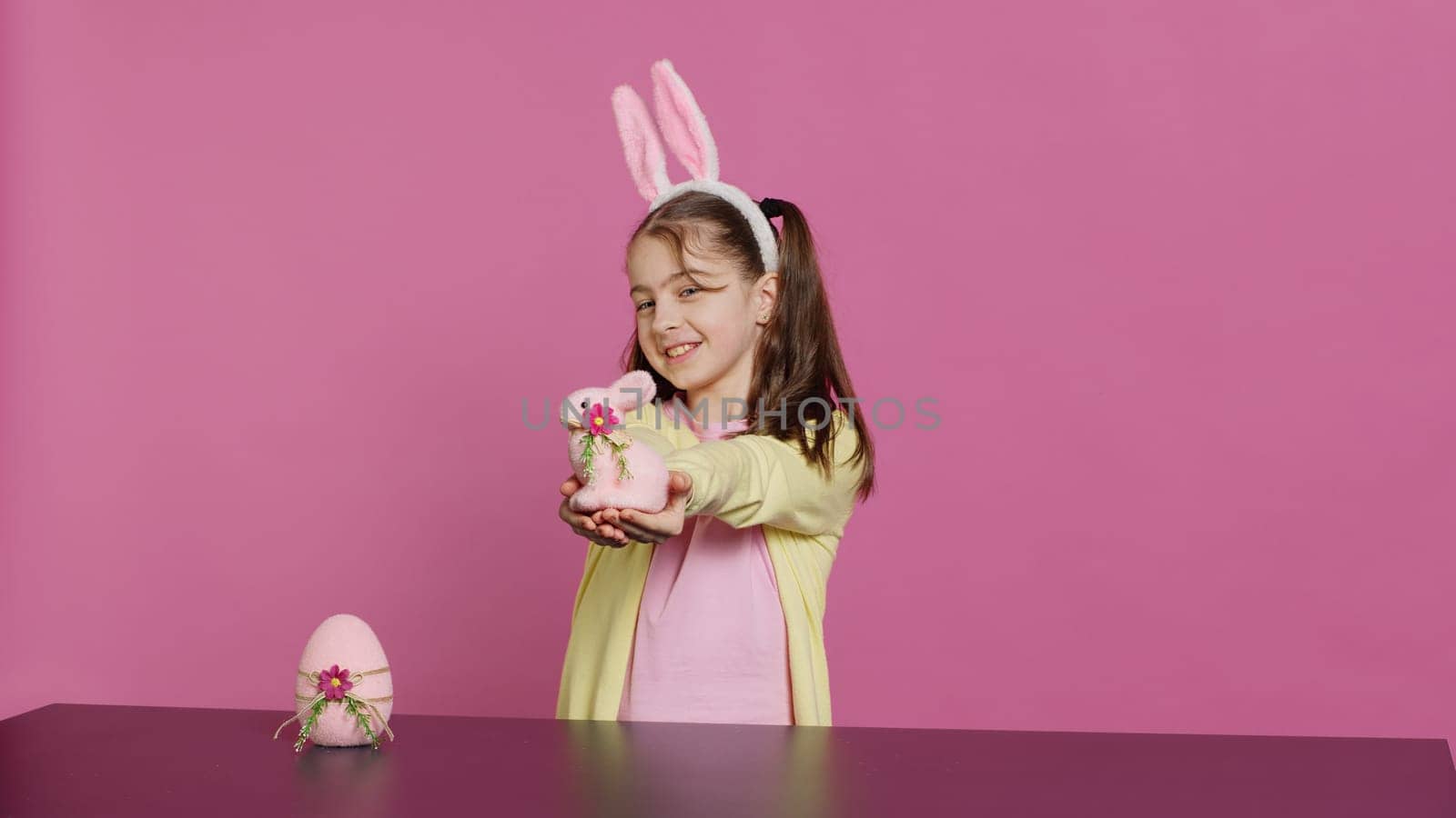 Smiling toddler with bunny ears showing her handmade easter ornaments by DCStudio