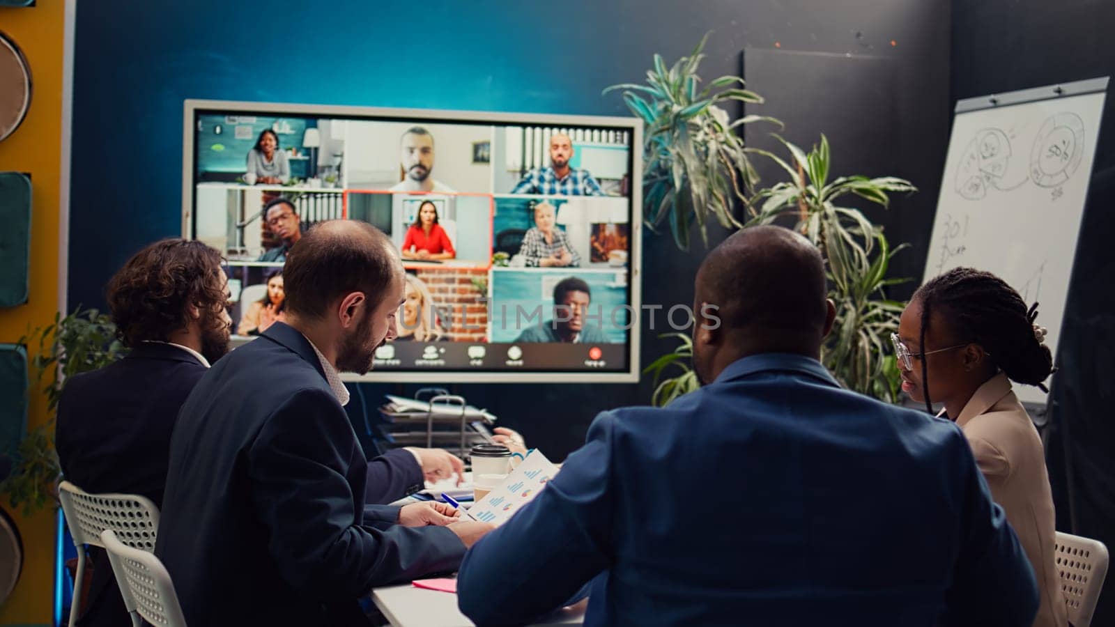 Business associates meeting with stakeholders on a videocall connection, sharing insight and updates on a new development project. Executive board members discussing about firm growth. Camera B.