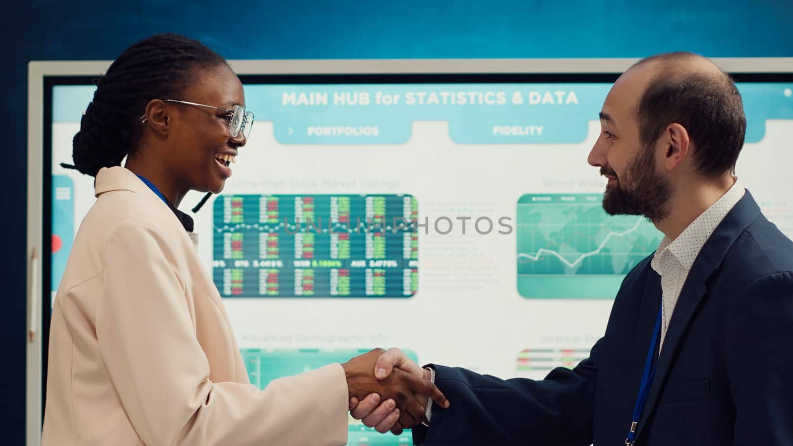 Business manager does handshake with a new employee during a briefing meeting, welcoming her to the team and presenting her to other staff members. Young man shaking hands with trainee. Camera A.