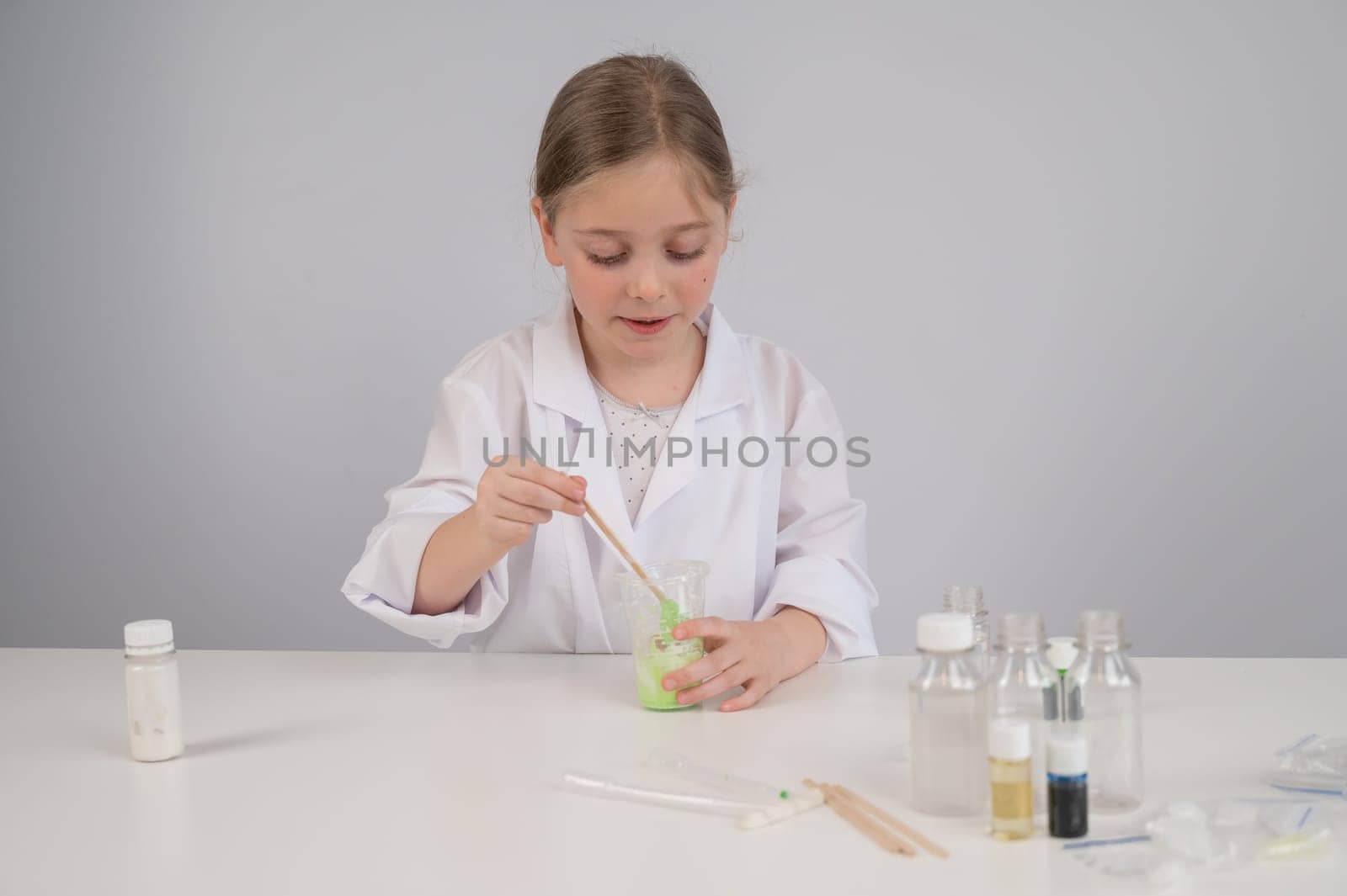 Caucasian girl doing chemical experiments on a white background. Making slime