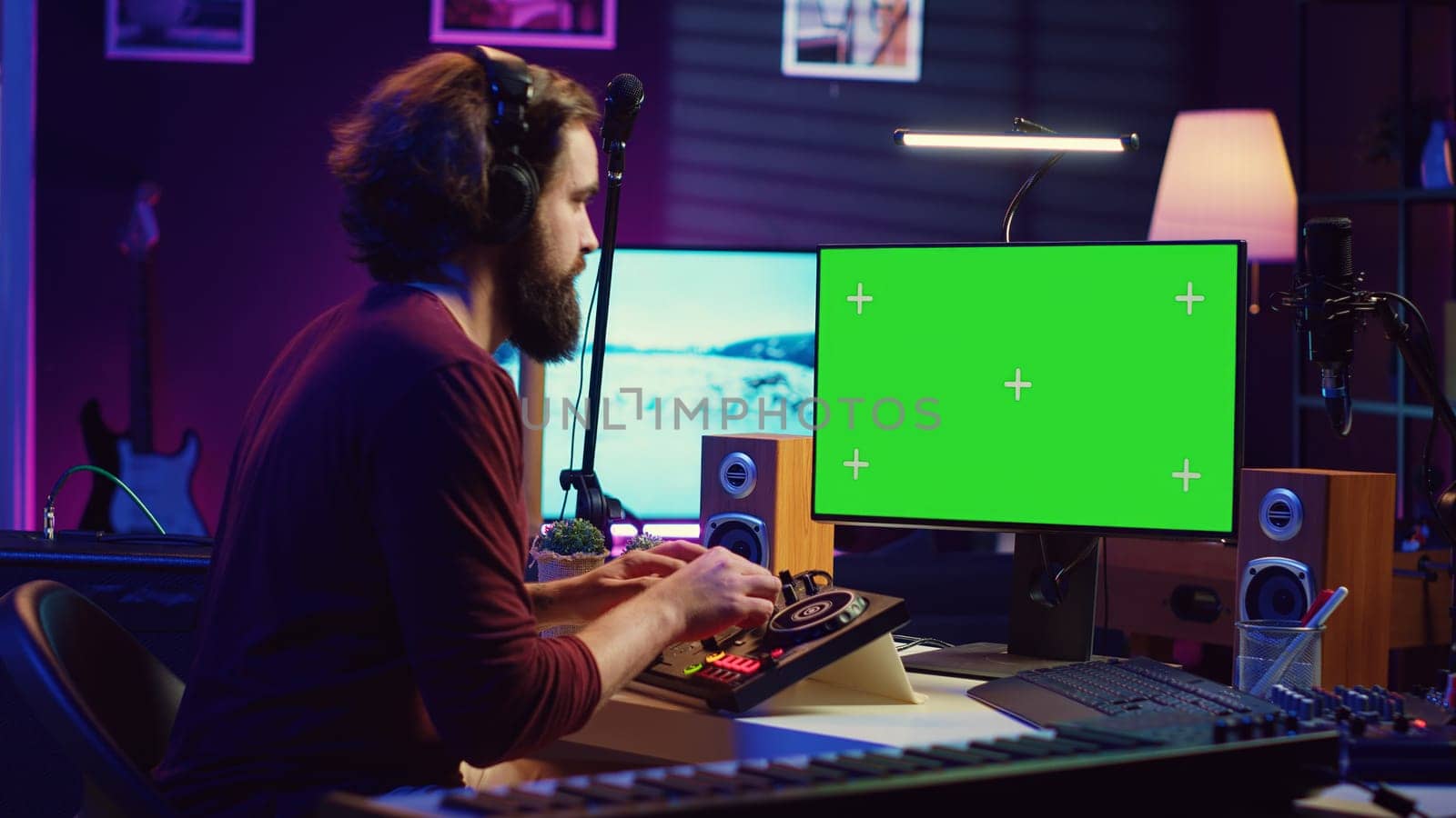 Music producer learning to use mixing console with online tutorial on computer, looking at isolated greenscreen display. Sound engineer practices editing sounds in his home studio. Camera A.