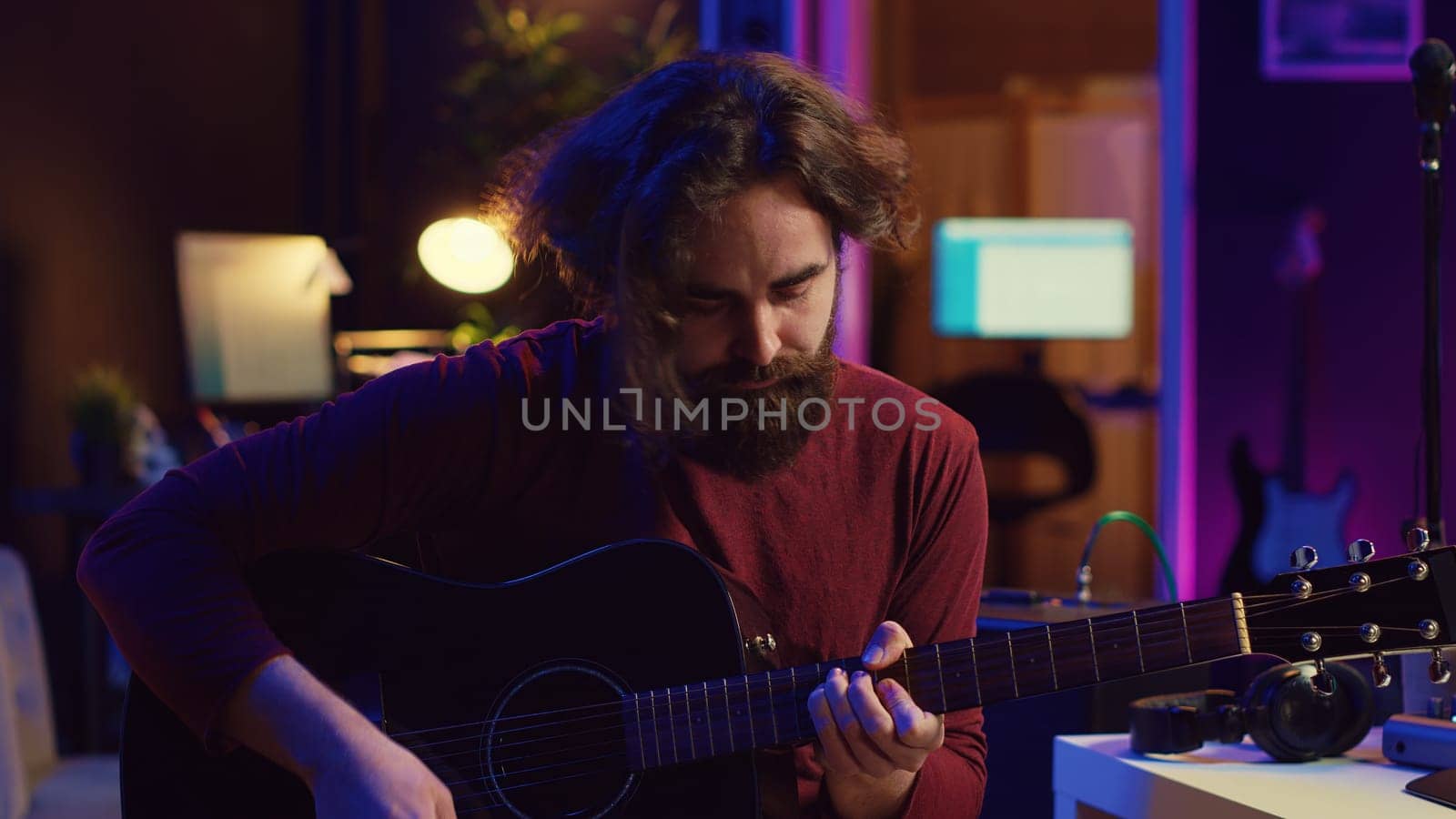 Young man playing guitar and creating music using equalizer daw software interface. Music producer recording song in home studio and mixing acoustic sounds on stereo console. Camera A.