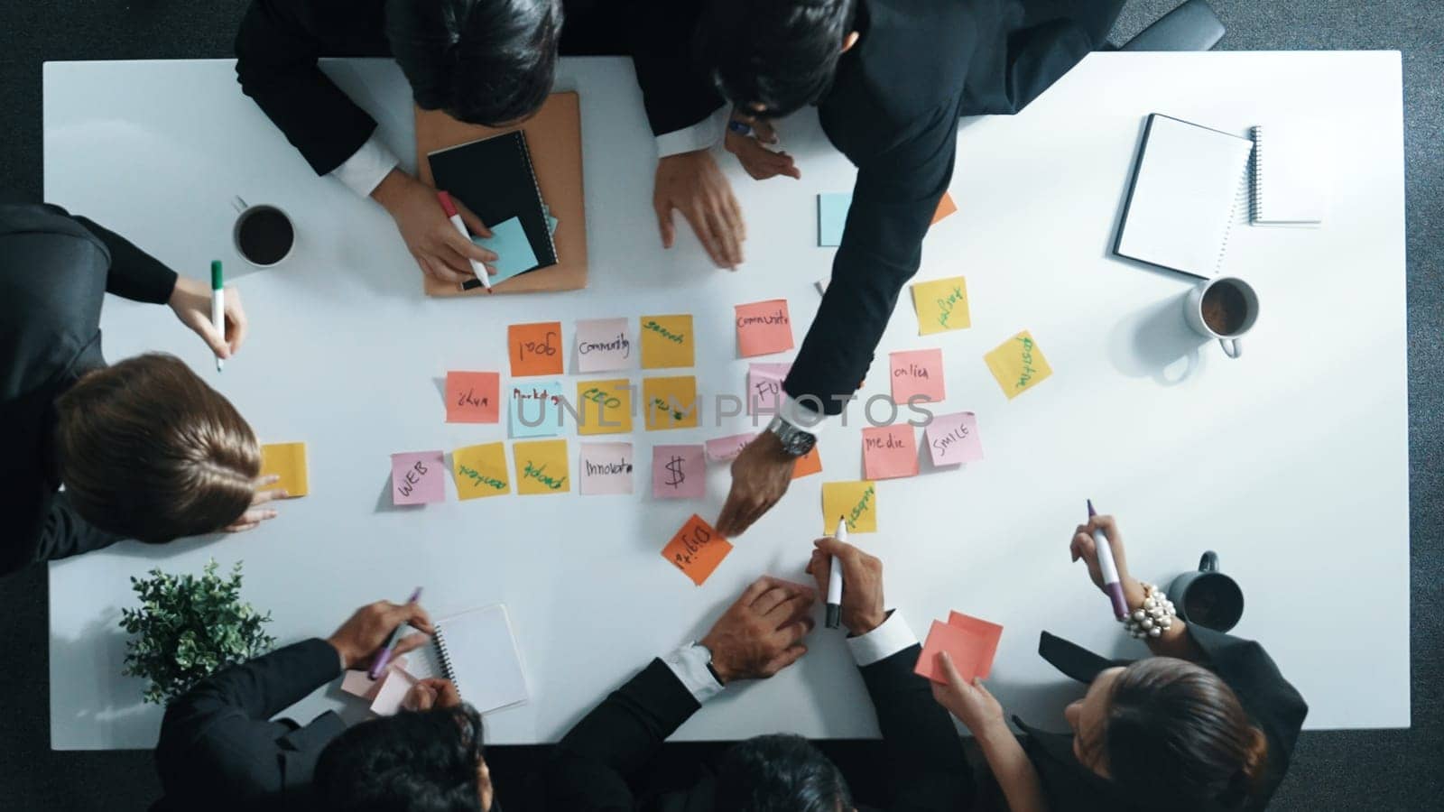 Top down aerial view of diverse business people writing marketing idea or taking a note on sticky notes. Professional executive manager group brainstorm financial plan at meeting room. Directorate.