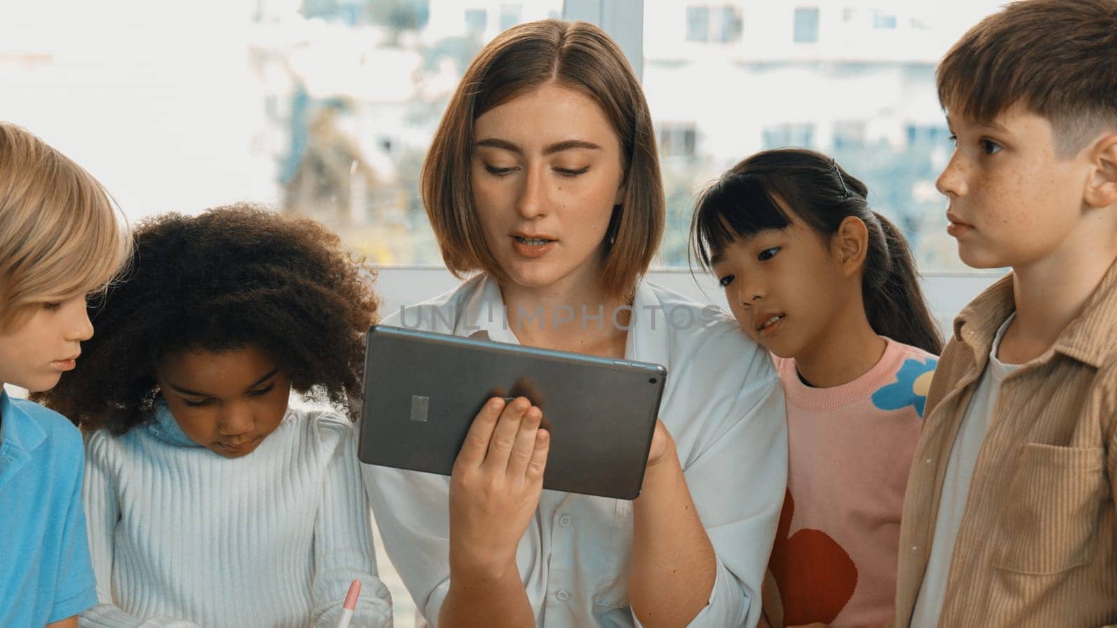 Smart teacher holding tablet while open online lesson to group of students. Skilled instructor explained engineering code lesson while young learner sitting and listening presentation. Erudition.