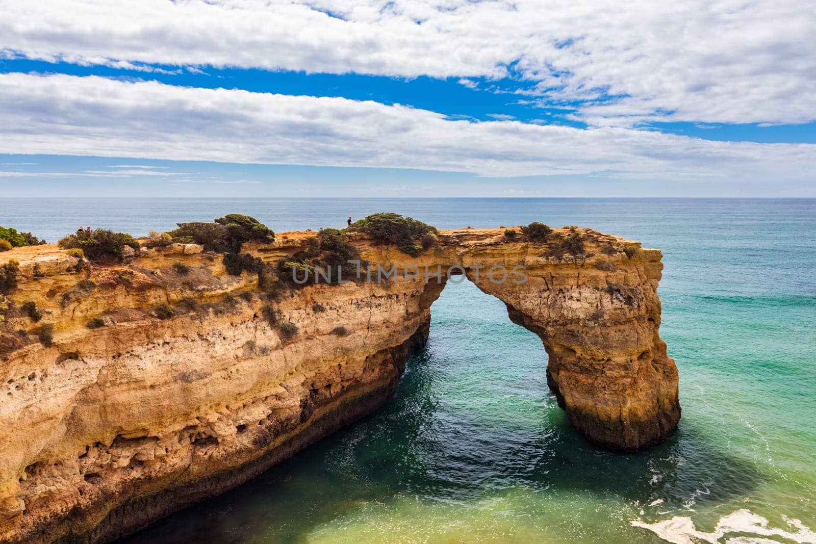 Natural arch above ocean, Arco de Albandeira, Algarve, Portugal. Stone arch at Praia de Albandeira, Lagoa, Algarve, Portugal. View of the natural arch Arco da Albandeira in the Algarve, Portugal.