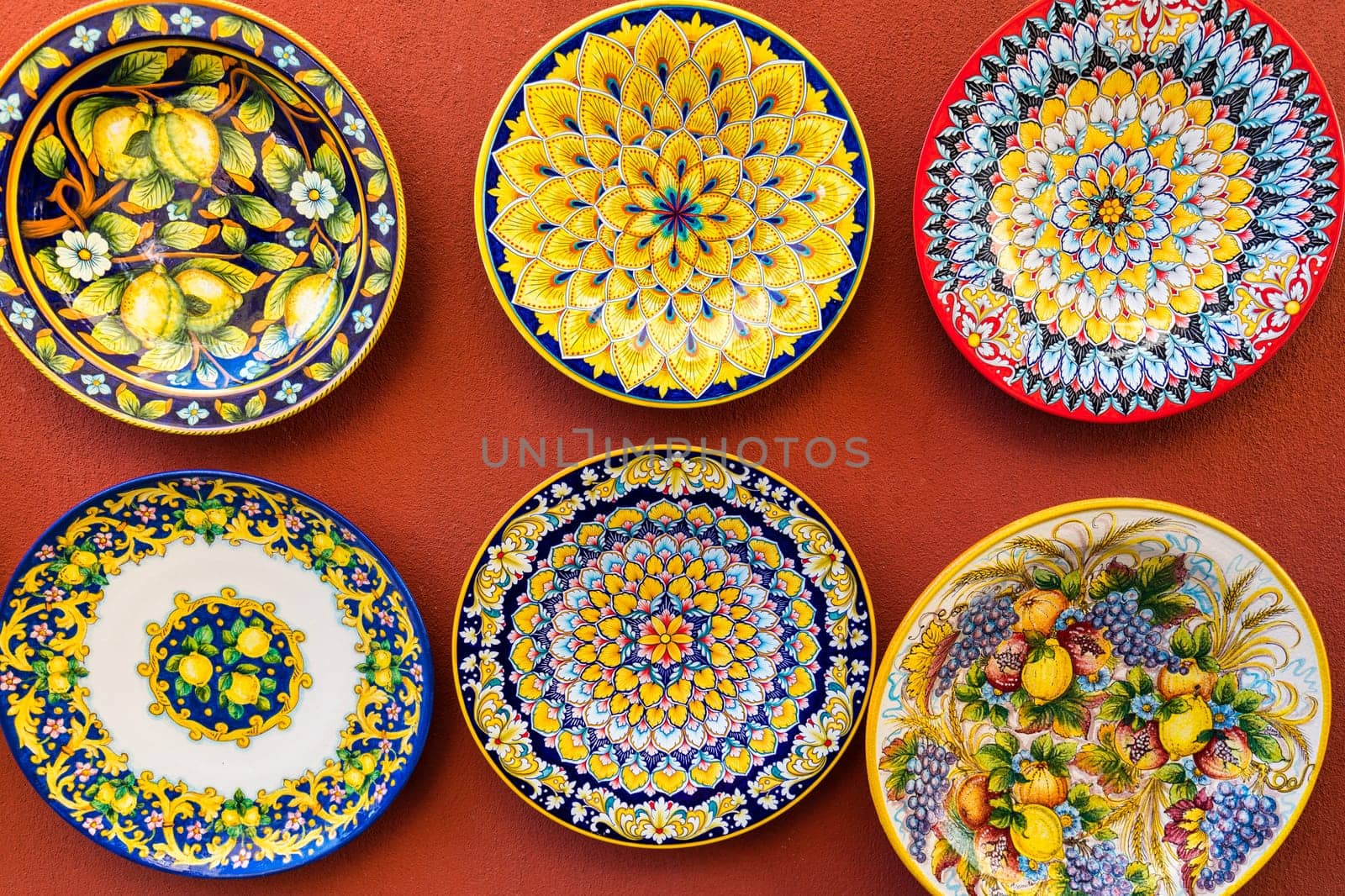 Collection of colorful plates with intricate designs hanging on a wall. The plates are arranged in a way that creates a sense of harmony and balance. Positano, Amalfi Coast, Italy.