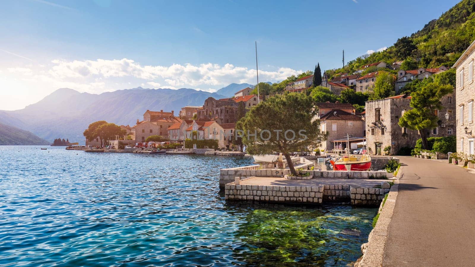 View of the historic town of Perast at famous Bay of Kotor on a beautiful sunny day with blue sky and clouds in summer, Montenegro. Historic city of Perast at Bay of Kotor in summer, Montenegro.