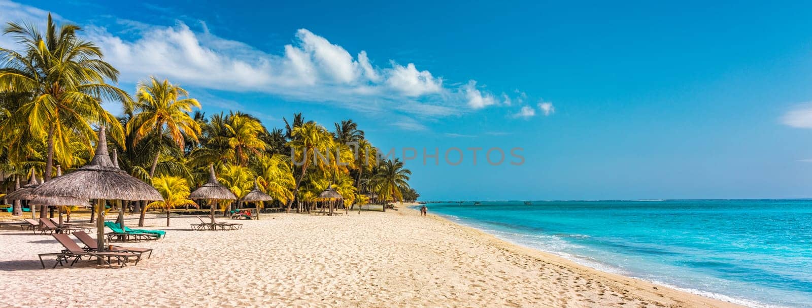 A beach with palm trees and umbrellas on Le morne Brabant beach in Mauriutius. Tropical crystal ocean with Le Morne beach and luxury beach in Mauritius. Le Morne beach with palm trees, white sand and luxury resorts, Mauritius. by DaLiu