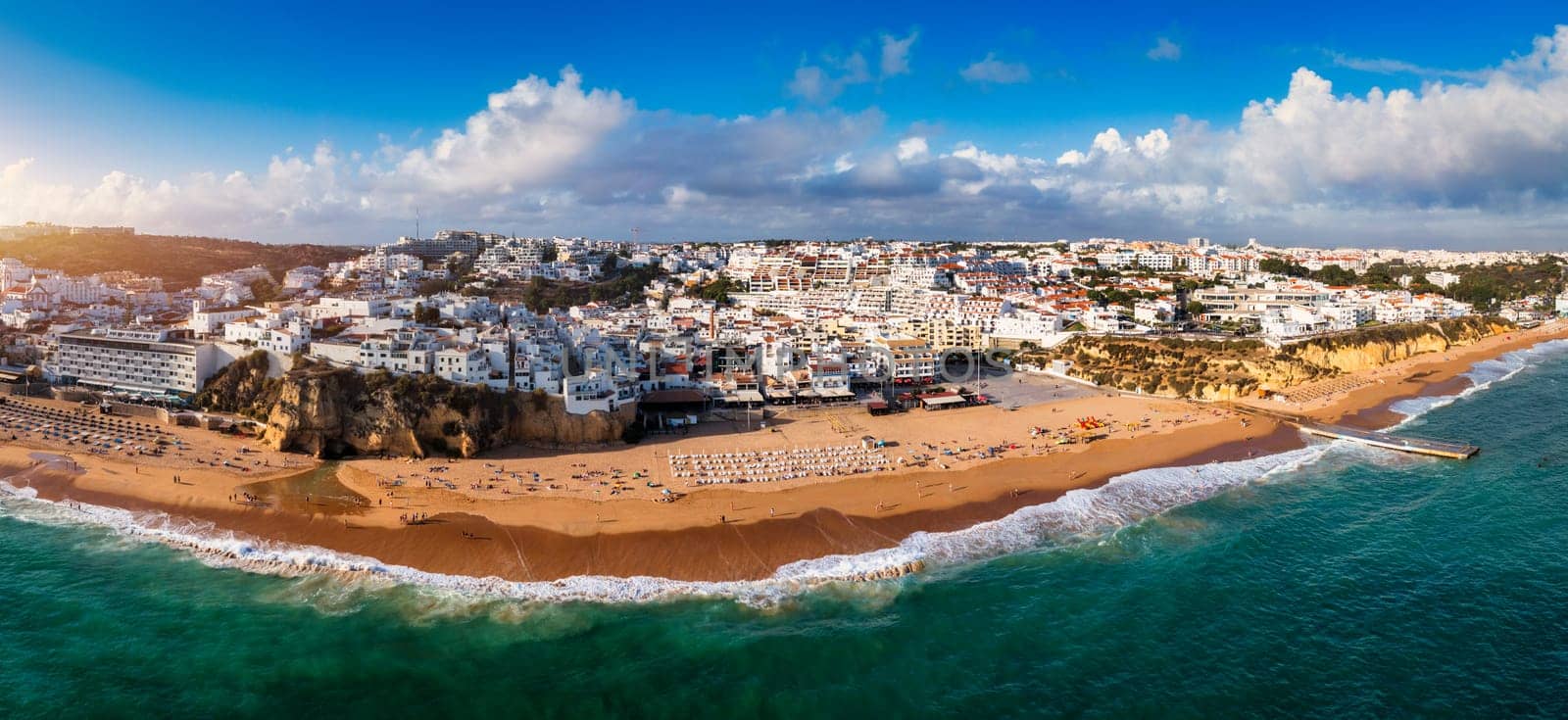 Aerial view of seaside Albufeira with wide beach and white architecture, Algarve, Portugal. Wide sandy beach in city of Albufeira, Algarve, Portugal. Aerial view of Albufeira town, Algarve, Portugal.