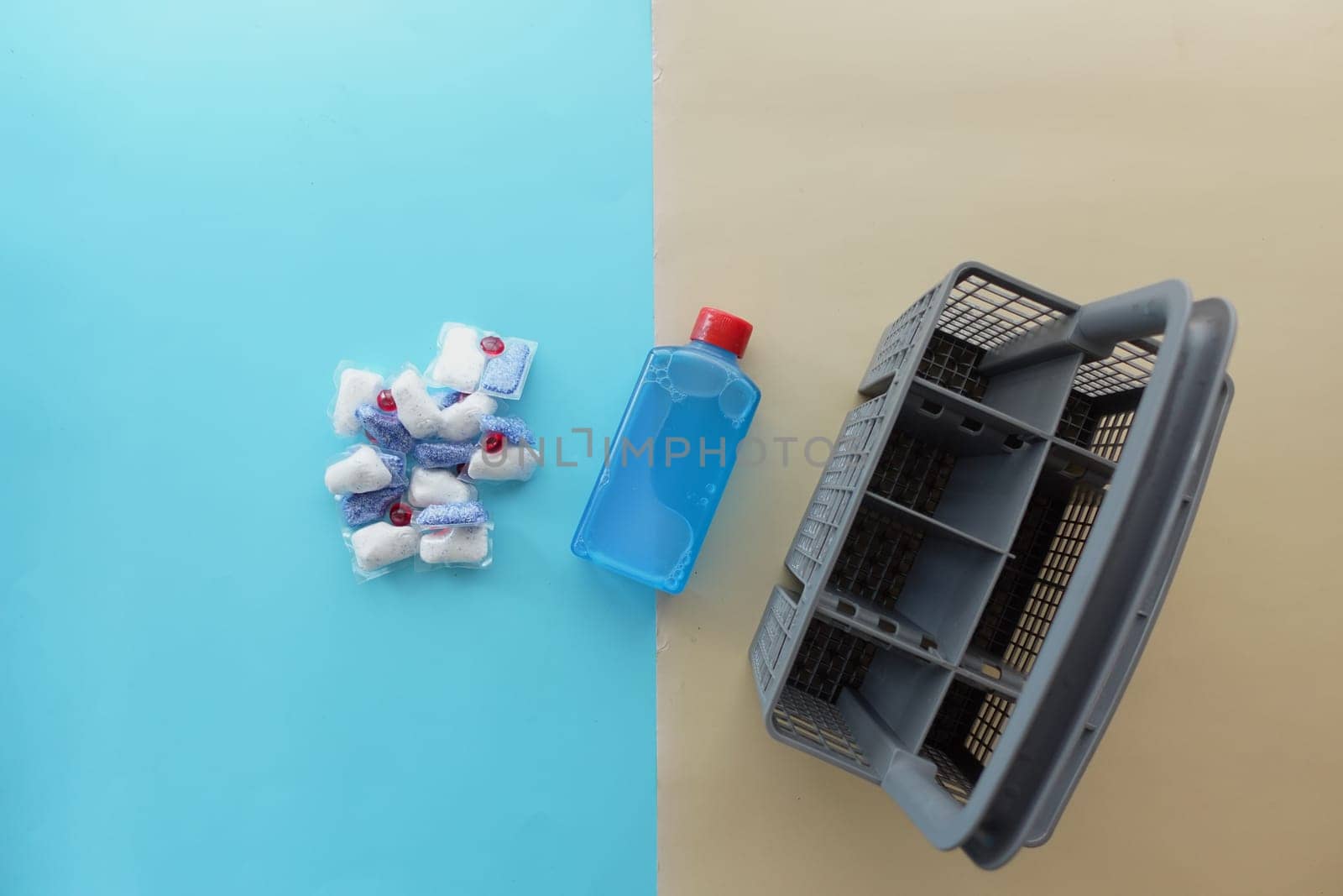 A stack of dishwasher tablets and a bottle of detergent on a blue background.