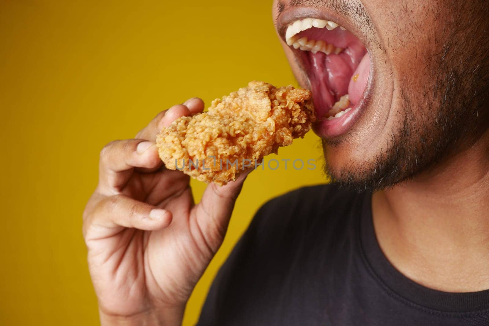 Man enjoying fried chicken, mouth open, savoring every bite with a big smile by towfiq007