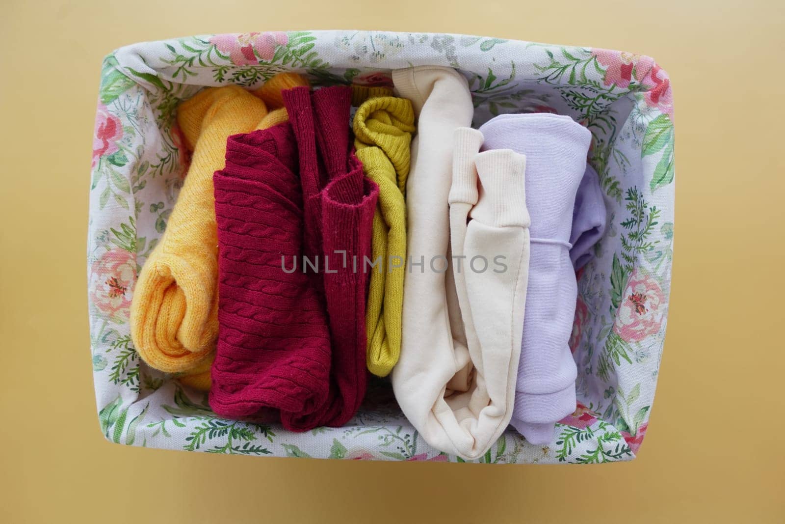 A rectangle violet basket of kid cloths on the table.