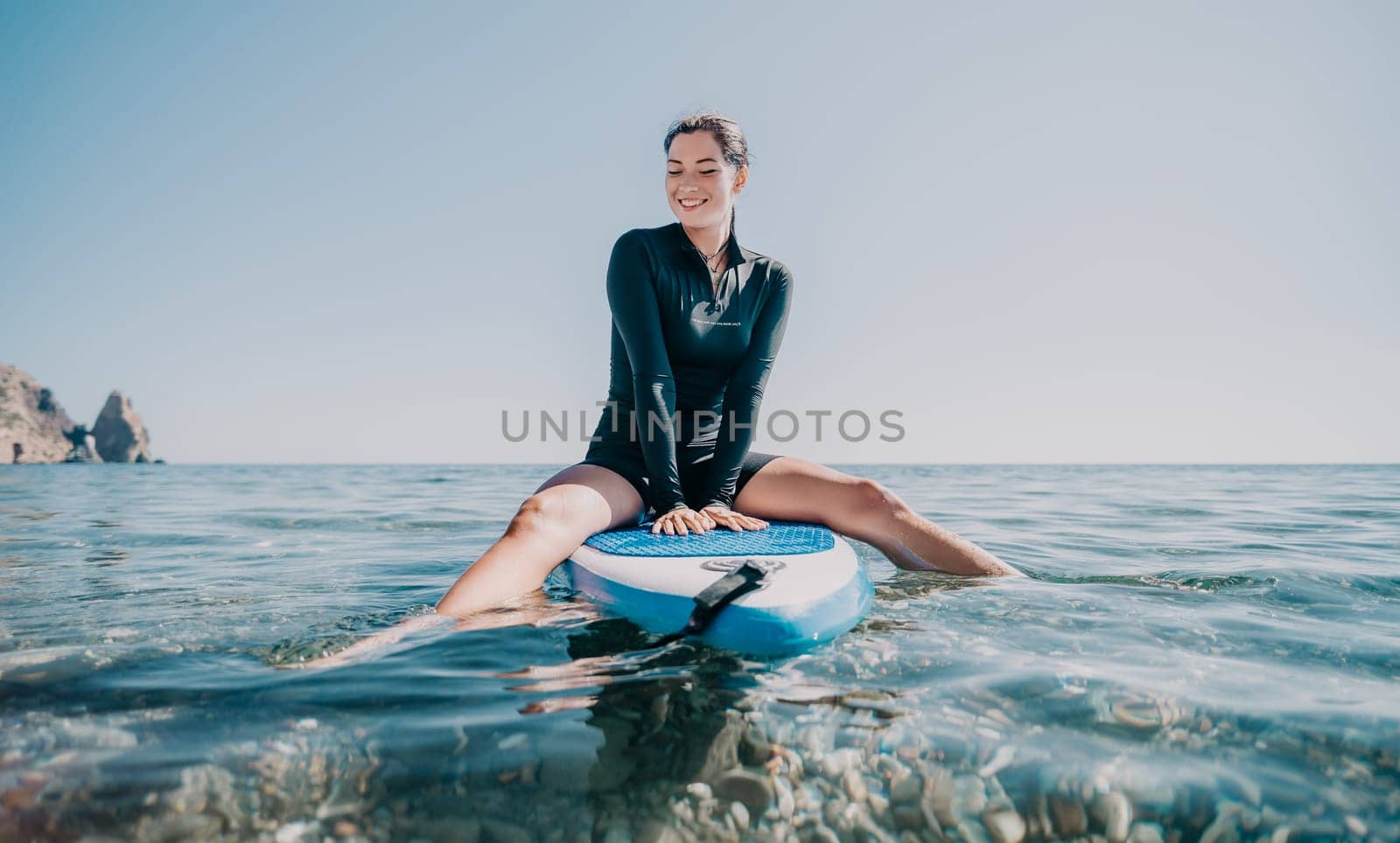 Woman sup yoga. Happy sporty woman practising yoga pilates on paddle sup surfboard. Female stretching doing workout on sea water. Modern individual female hipster outdoor summer sport activity. by panophotograph