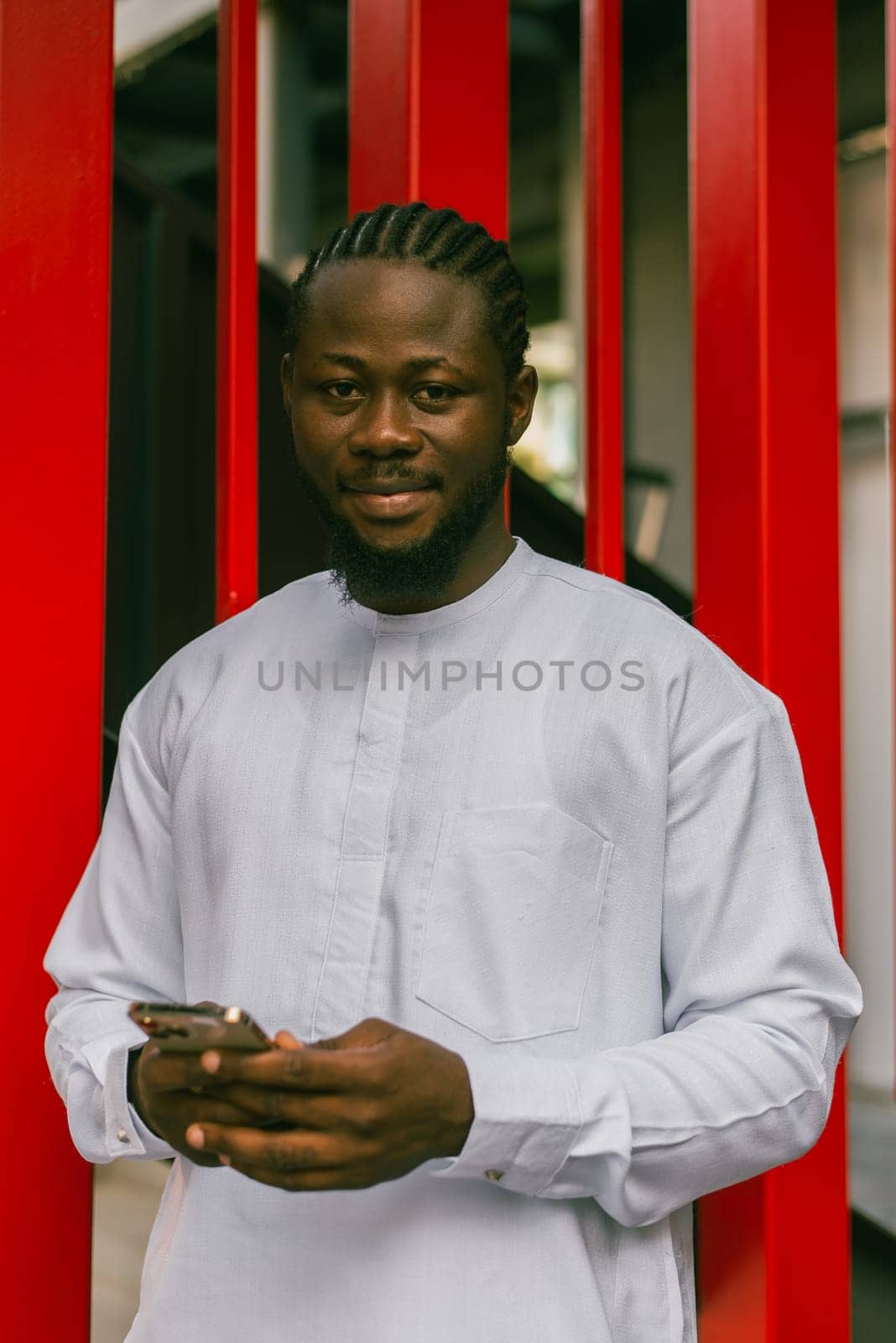 Cheerful male tourist portrait dress in white wear dashiki ethnic smiling at city street or small town background. African American travel model have free time. Millennial generation and gen z people.