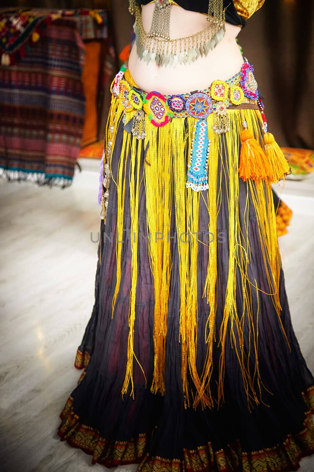 Diverse group of women wearing vibrant, multi-colored dress and tassels dancing tribal on ethnic celebratory event