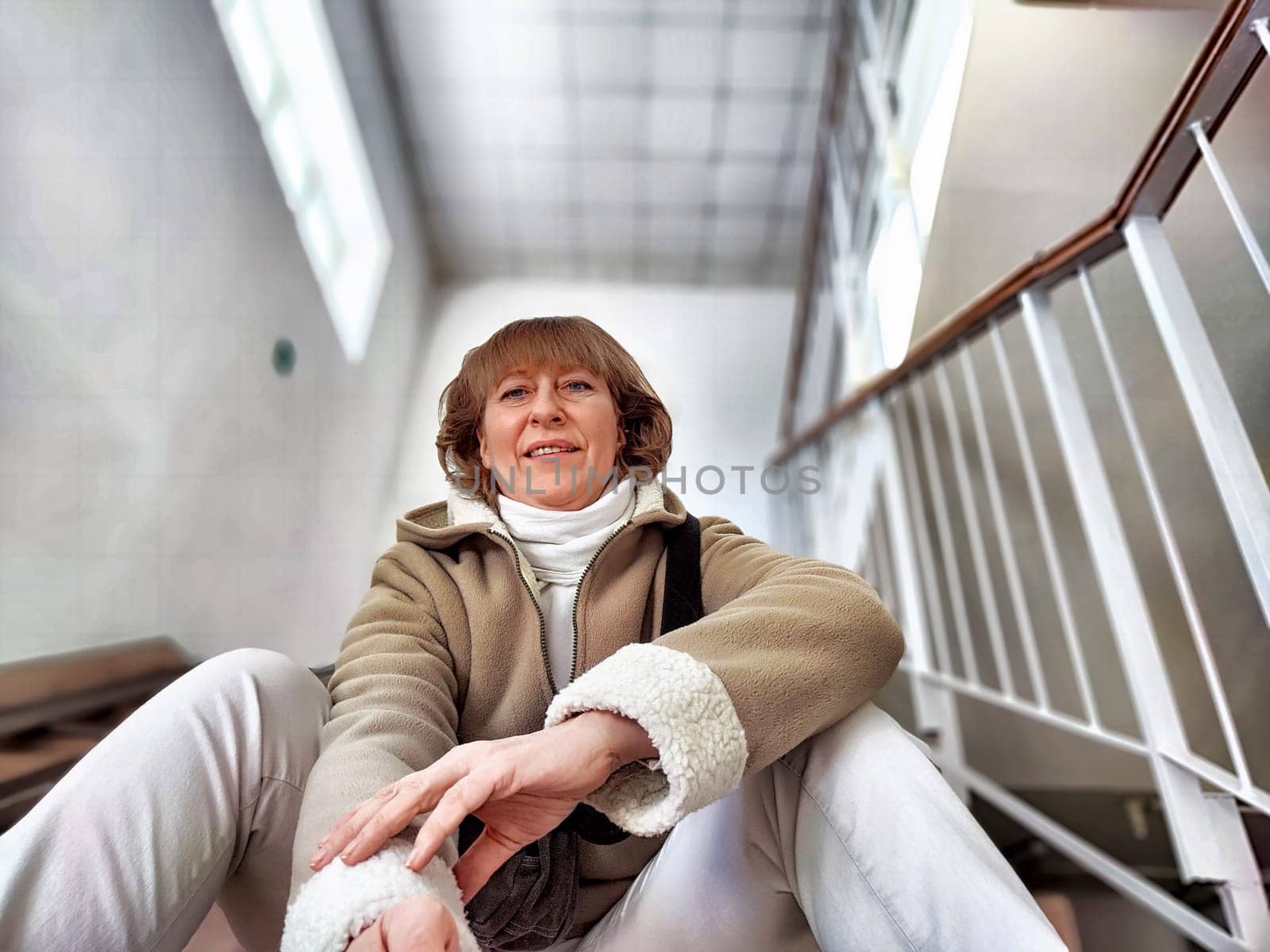 Cute girl on Indoor Staircase. Mature middle aged woman taking selfie indoors