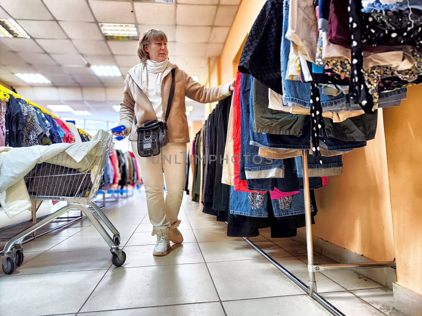 Middle-Aged Woman Selecting Clothes During Shopping Trip. Shopping for apparel in clothing store. Shopaholic