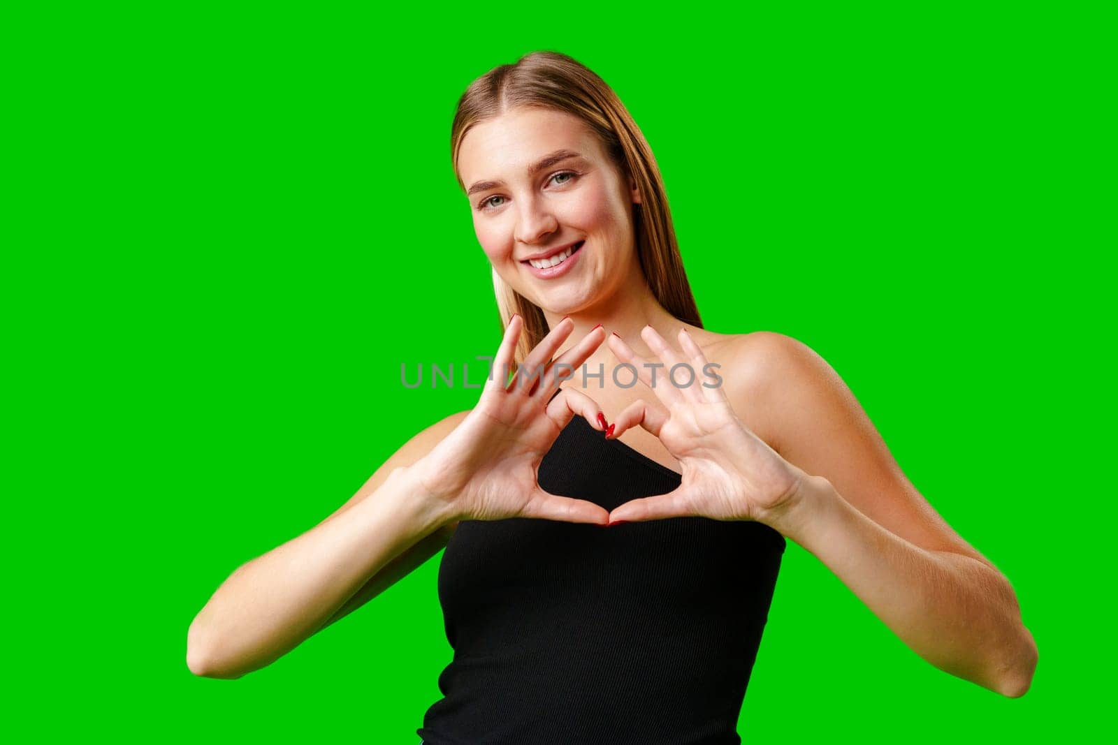 Young Woman Making Heart With Hands on green background by Fabrikasimf