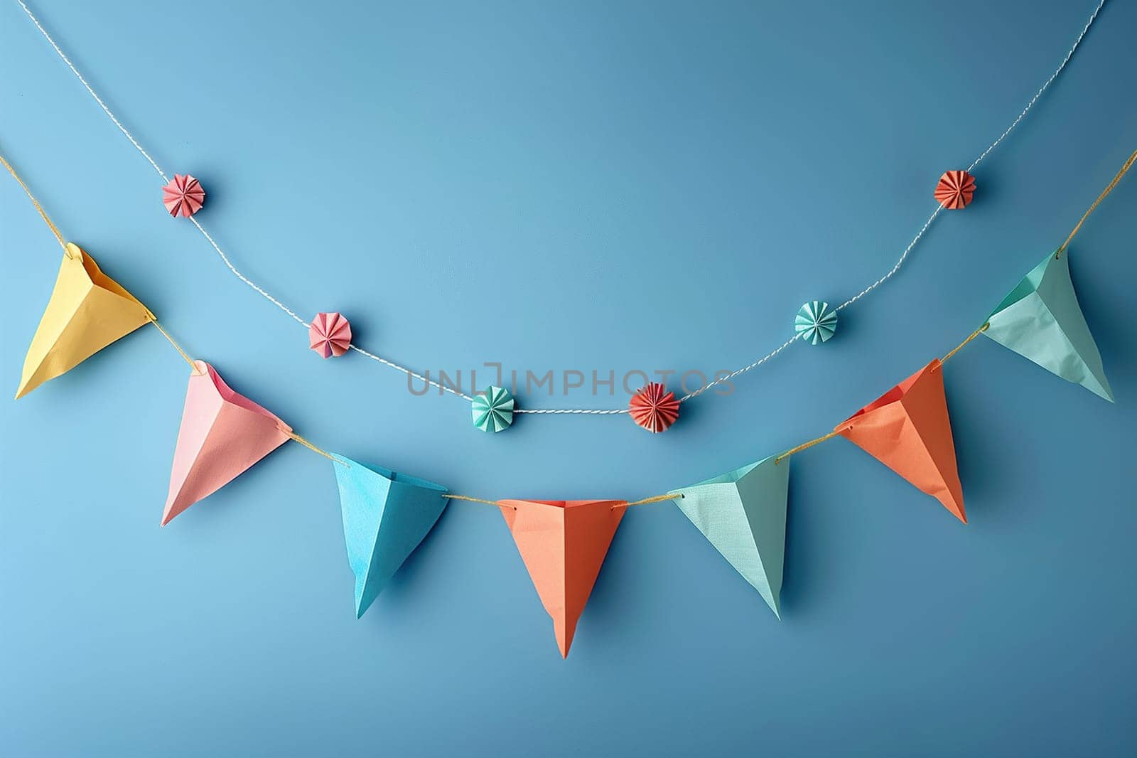Colorful holiday flags in the form of a garland on the blue wall. The garland hangs in two rows. Congratulatory background with place for text. Holiday concept by Vovmar
