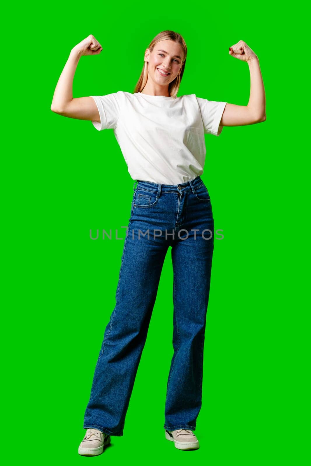 Happy Young Woman Raising Fists against green background in studio