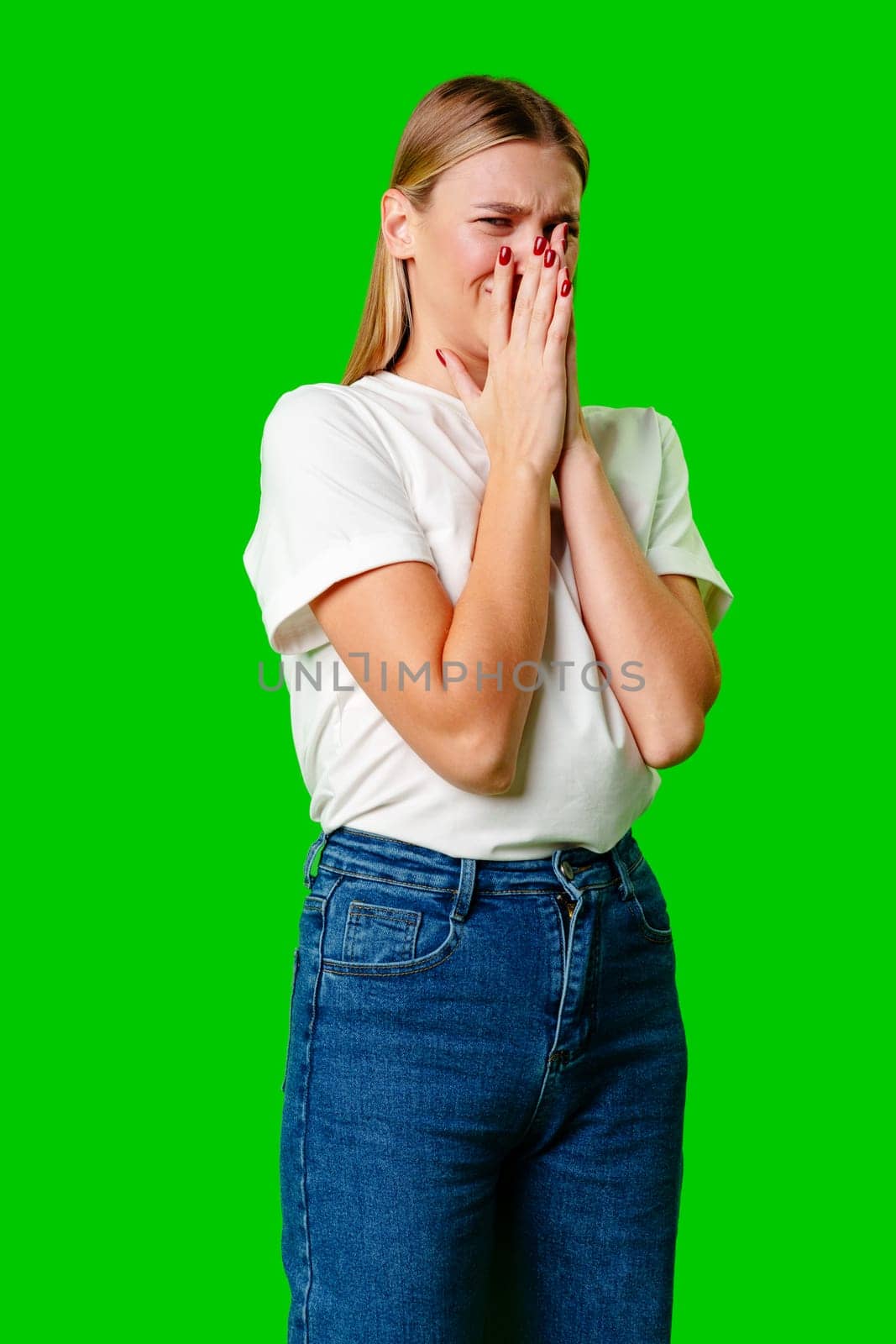 Portrait of an upset young casual girl against green background in studio