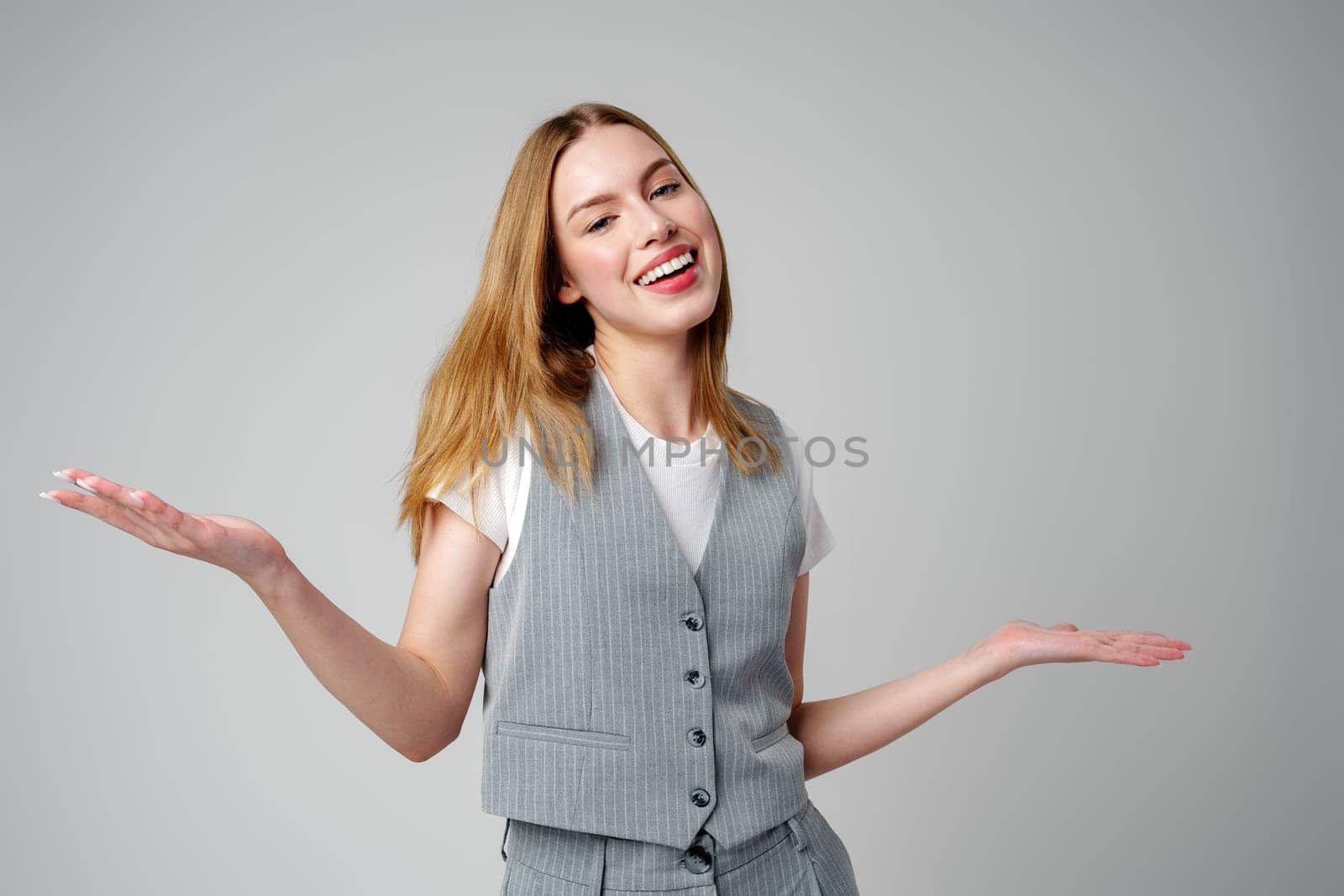 Joyful Young Blonde Woman Smiling against gray background by Fabrikasimf