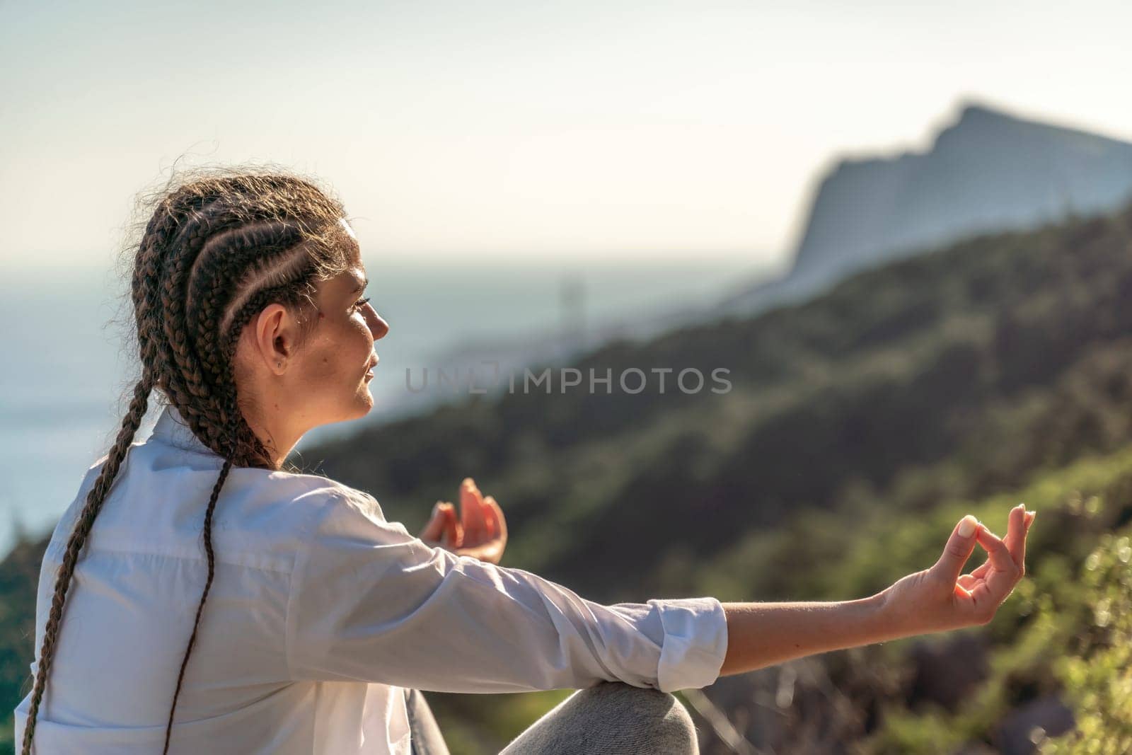 woman doing yoga in the top of a cliff in the mountain. Woman meditates in yoga asana Padmasana by Matiunina