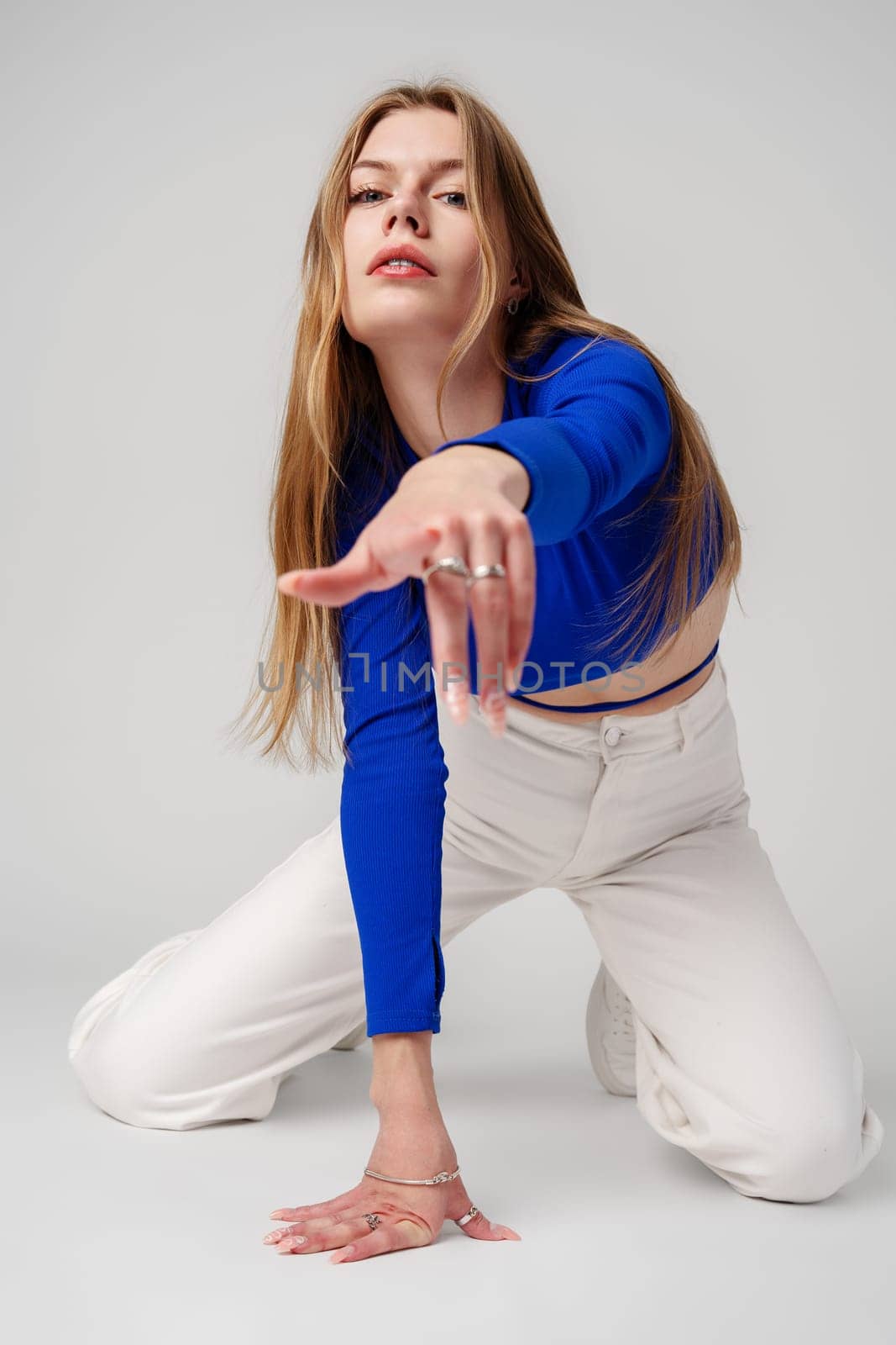 Young Woman model in Blue Top and White Pants posing on white background by Fabrikasimf