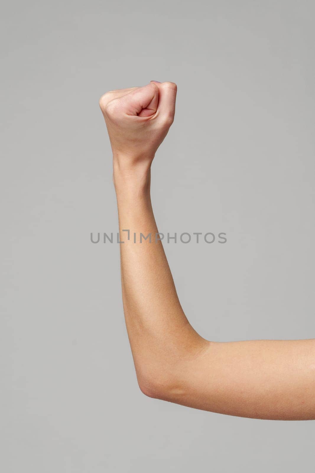 Female hand with clenched fist on gray background in studio