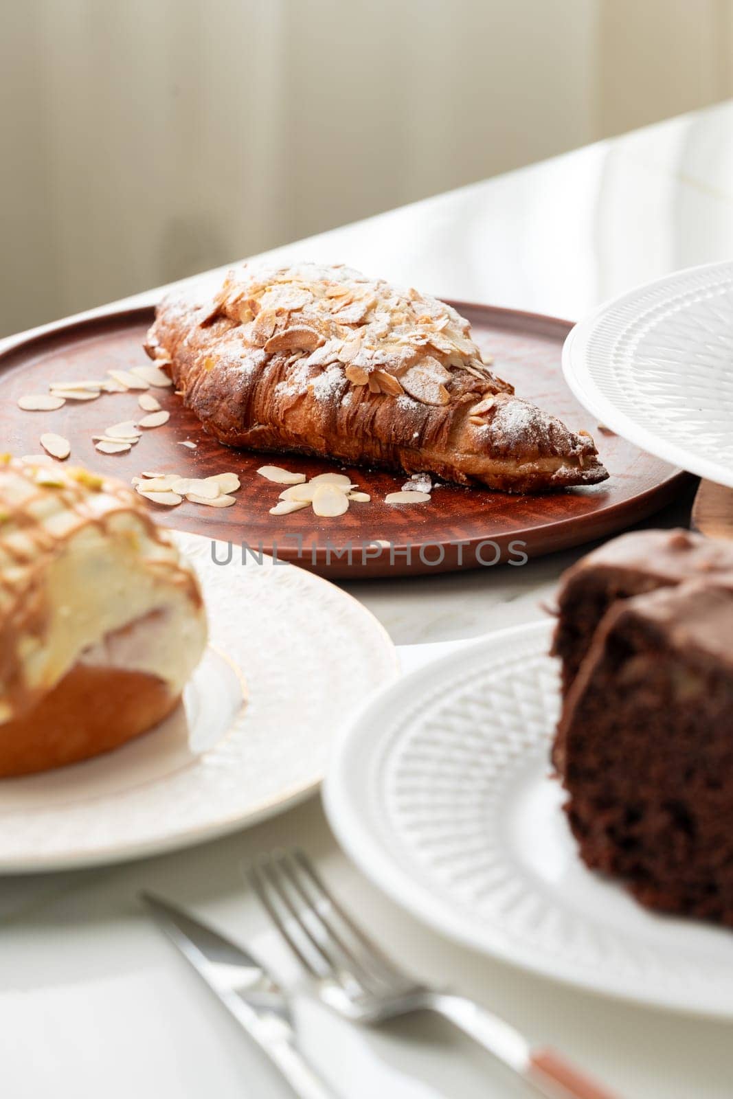 Homemade desserts sponge cake and cinnamon bun on table by Fabrikasimf