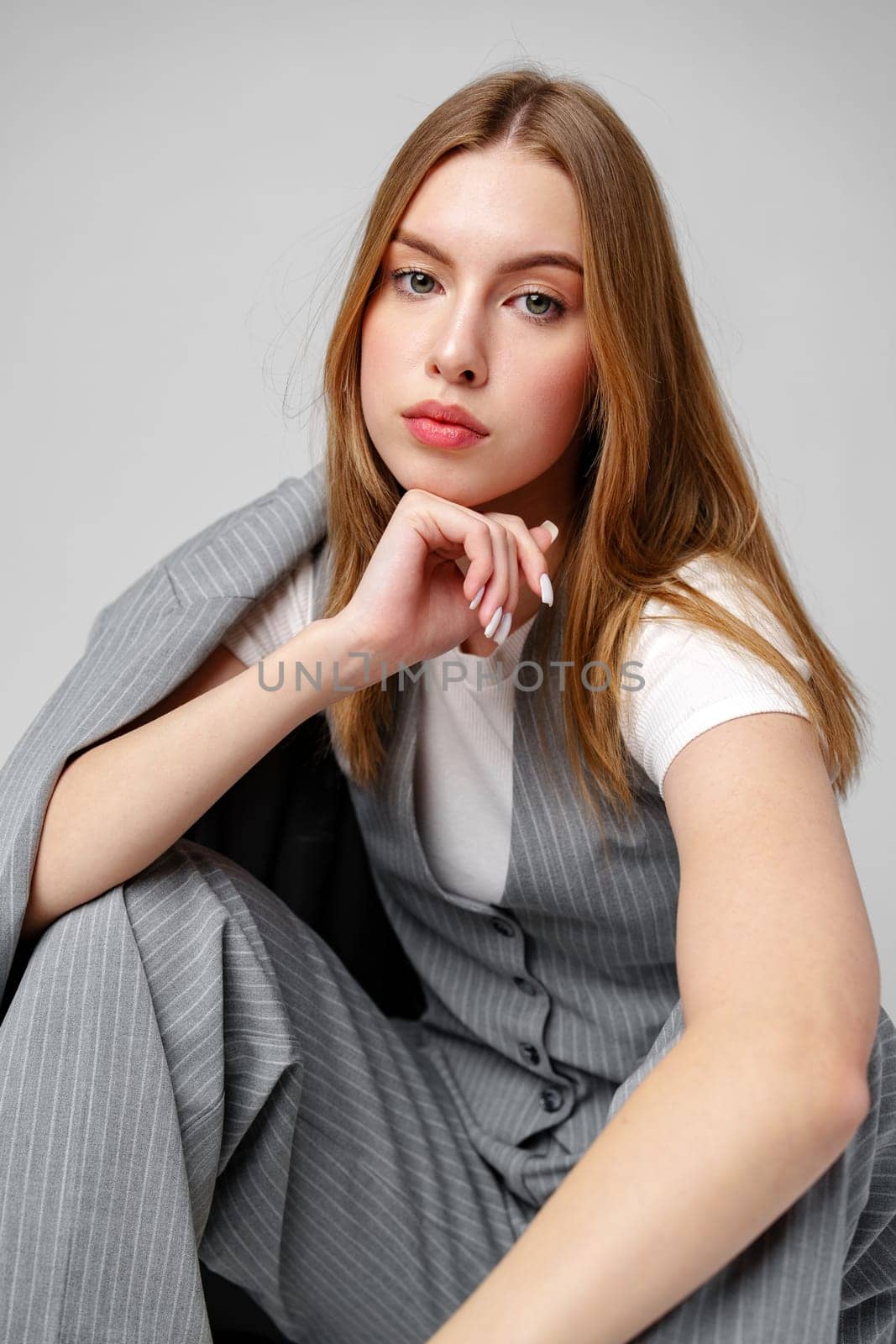 Young Woman in a Gray Suit Sitting on the Floor in Studio by Fabrikasimf