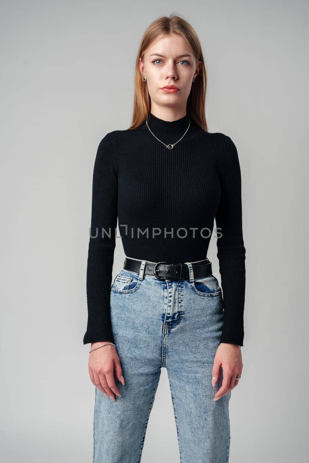 Young Woman Wearing Black Top and Jeans against gray background by Fabrikasimf