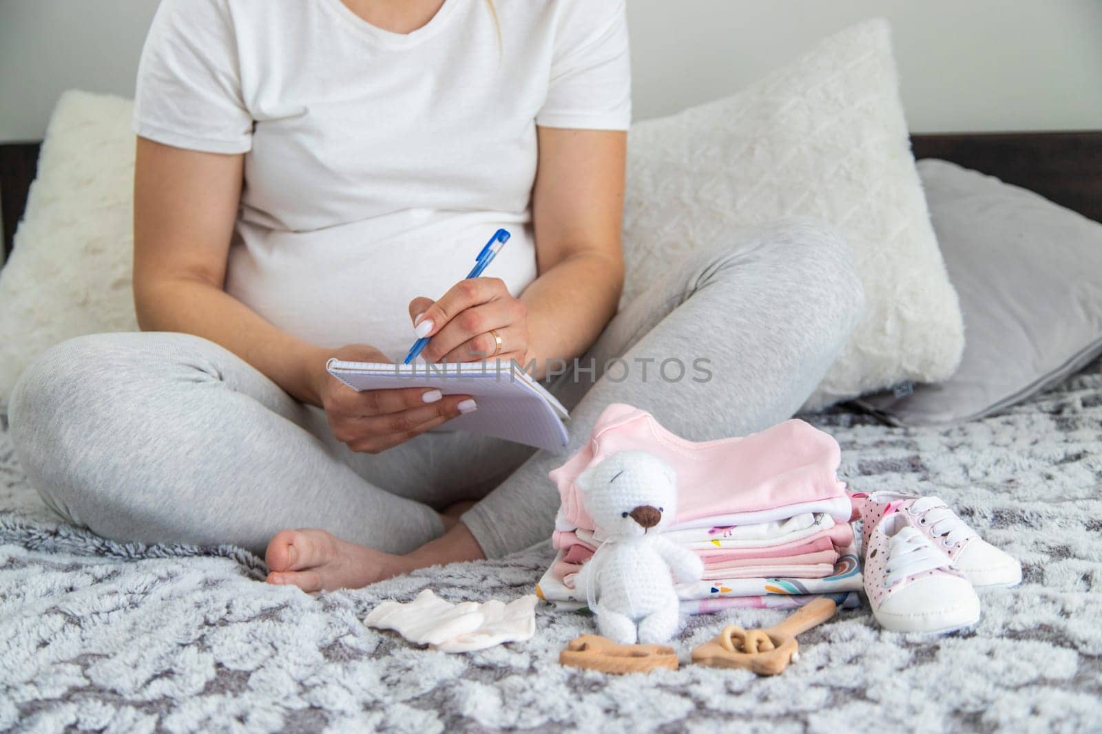 A pregnant woman collects baby things. Selective focus. Home.