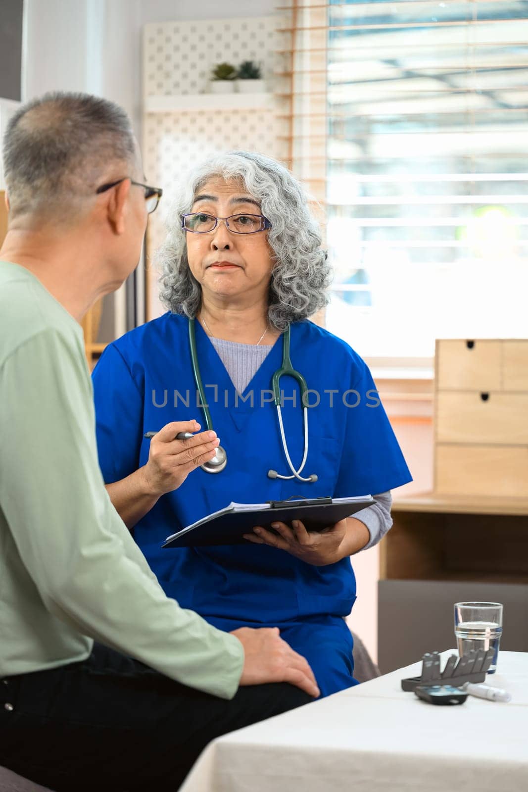 Mature healthcare worker explaining the medical results to patient during home visit.