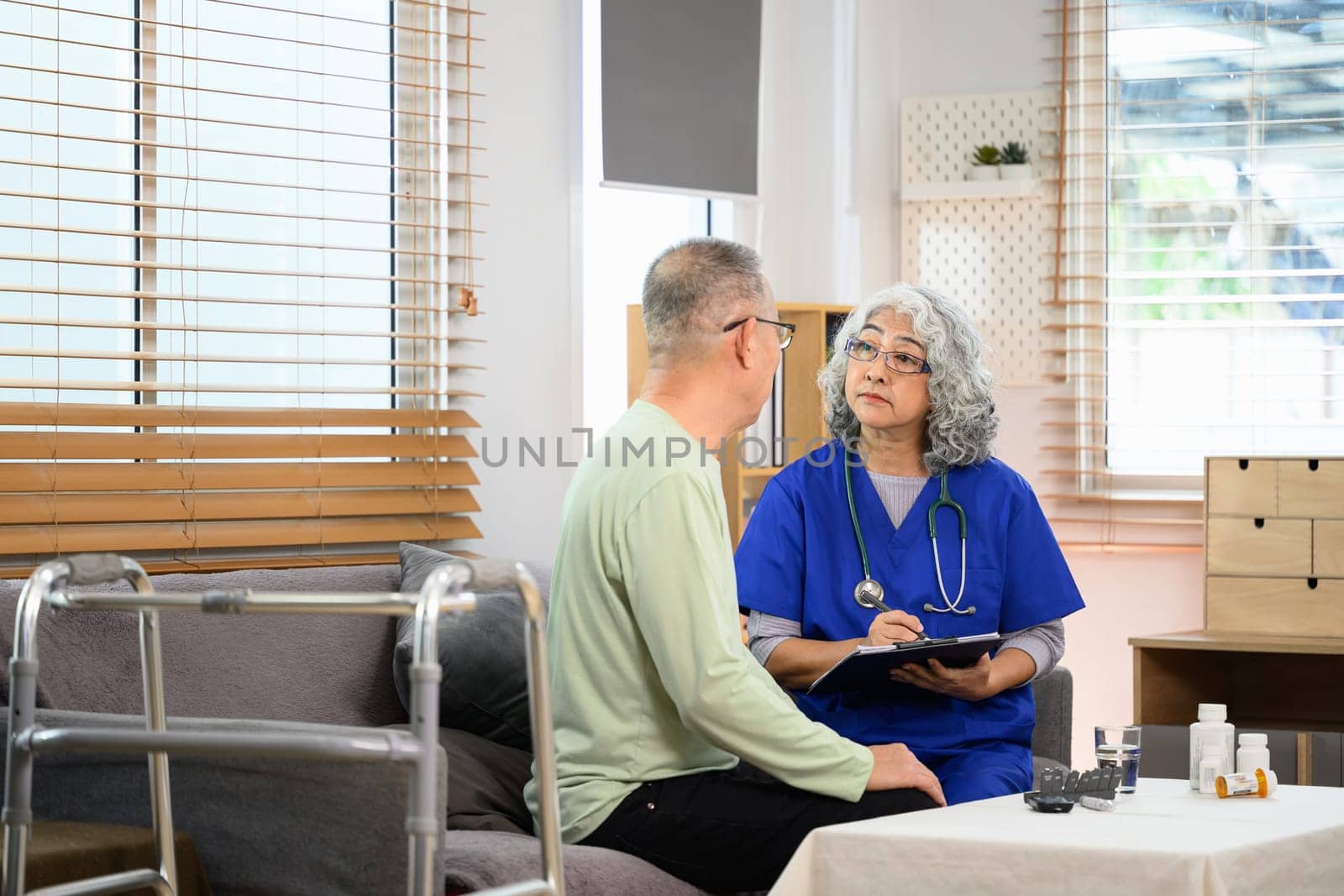 Mature healthcare worker explaining the medical results to patient during home visit.