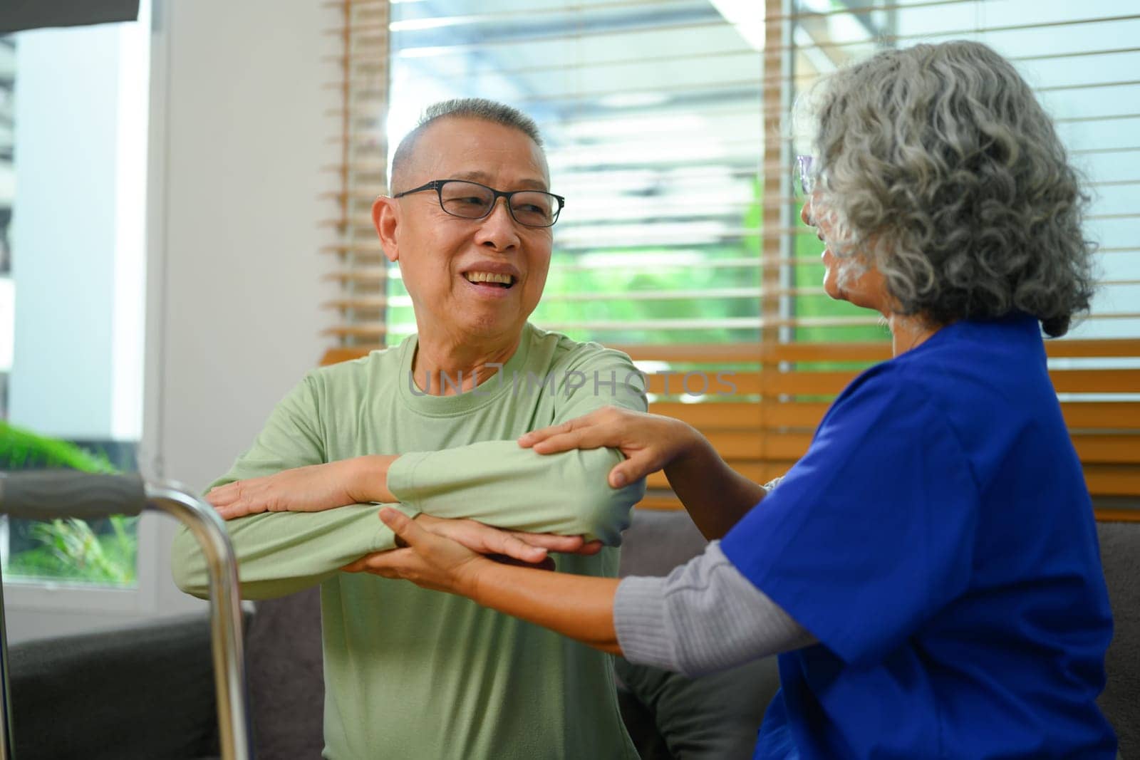 Senior male patient doing physical exercises with his physiotherapist at home. Rehabilitation and healthcare concept by prathanchorruangsak