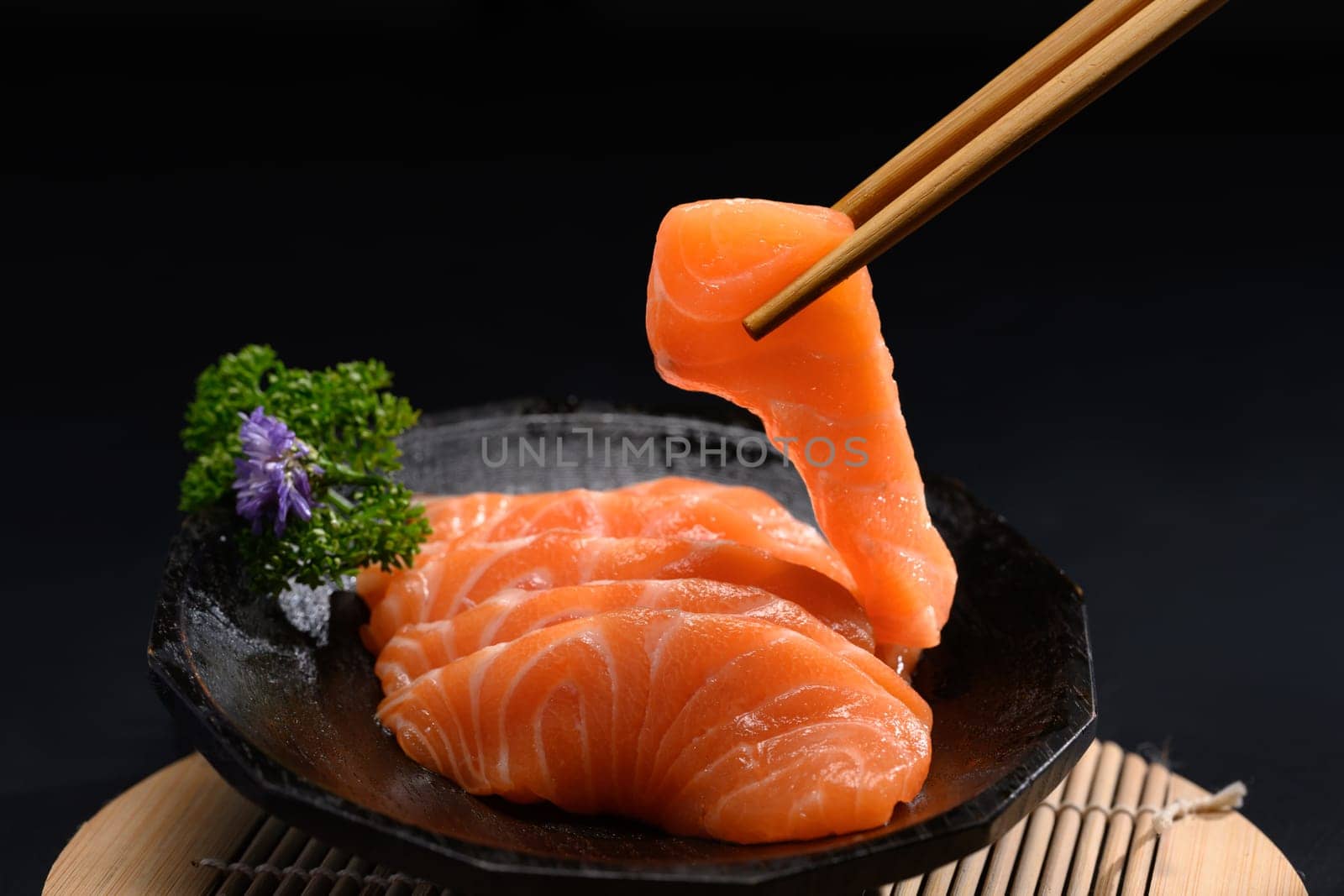Japanese food, Salmon sashimi with parsley leaf on black plate.