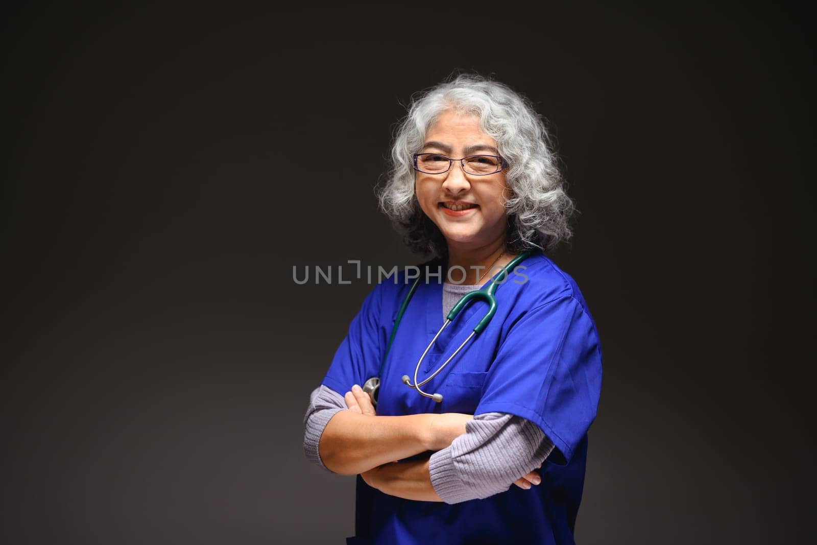 Friendly senior woman doctor standing against black background. Medicine and health care concept by prathanchorruangsak