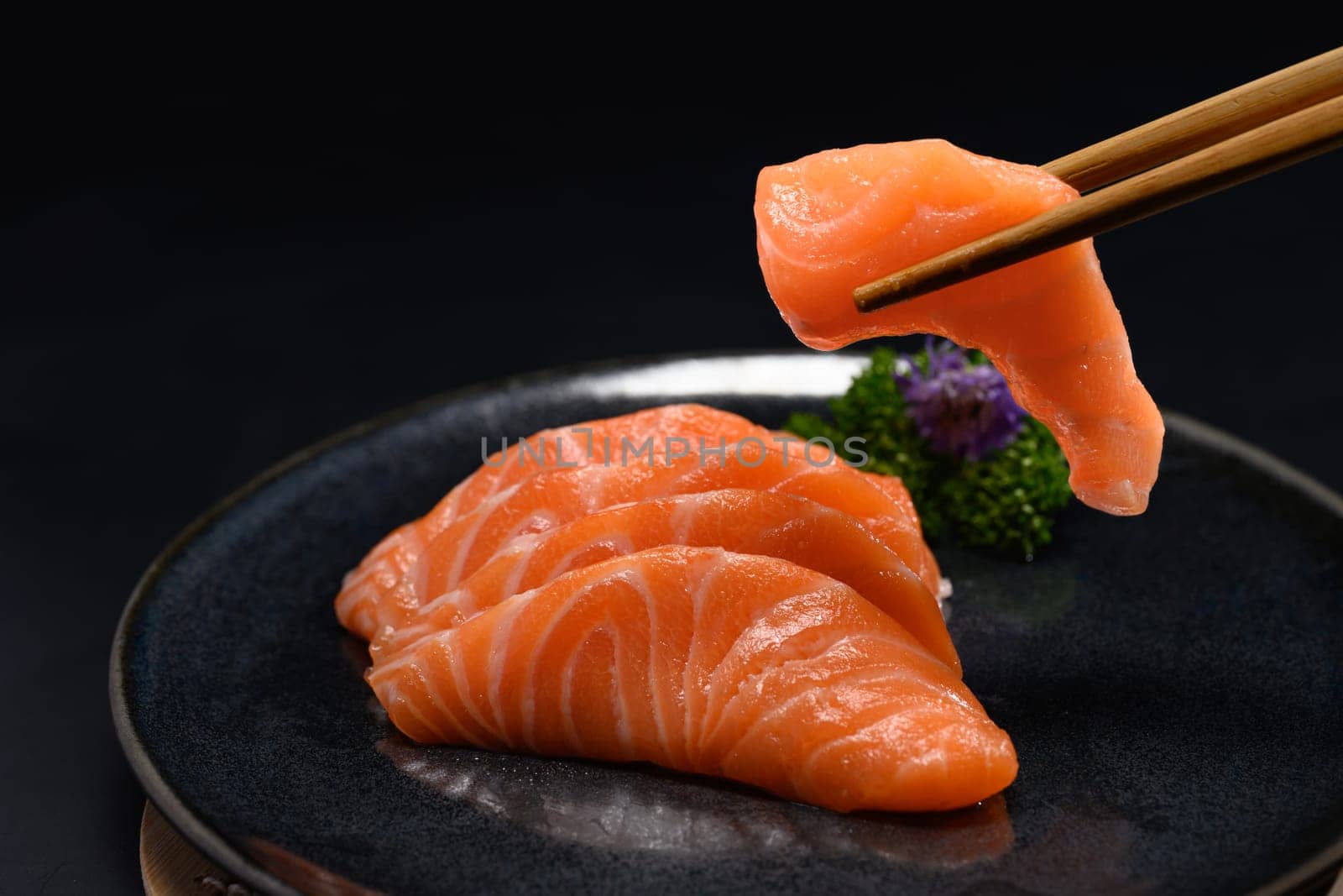 Sliced fresh salmon sashimi serve on a black Japanese style plate, Closeup shot by prathanchorruangsak