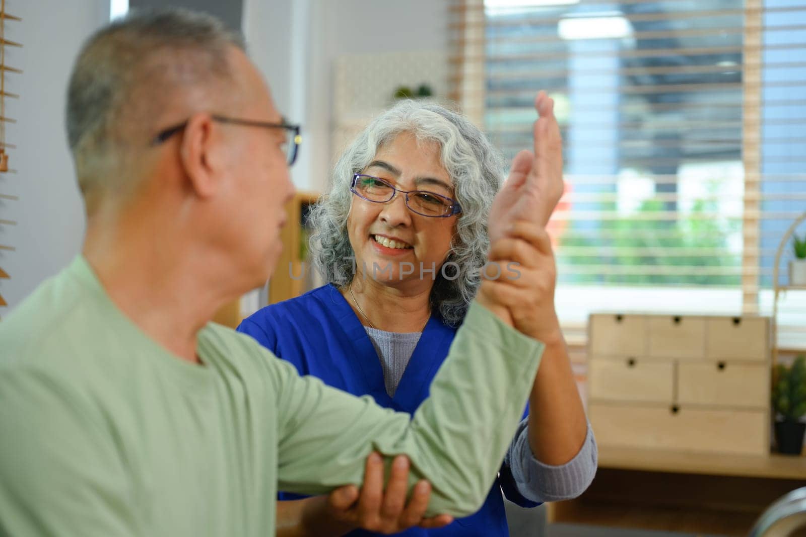 Caring nurse helping senior man with physical therapy at home. Healthcare concept.