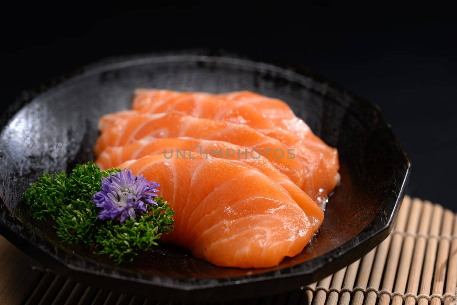Salmon sashimi on black plate with parsley leaf. Japanese food style.