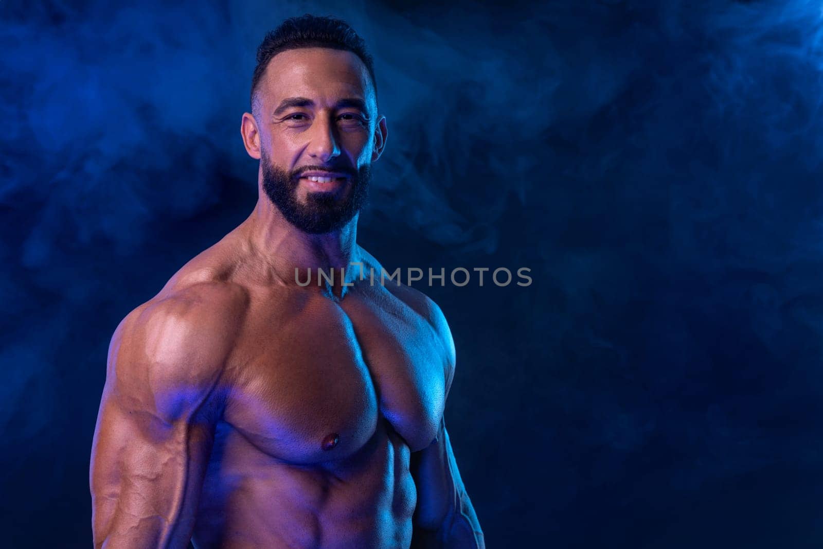 Bodybuilder in neon colors. Athlete man posing on black background. Sports concept. Bodybuilding competition. Social media template.
