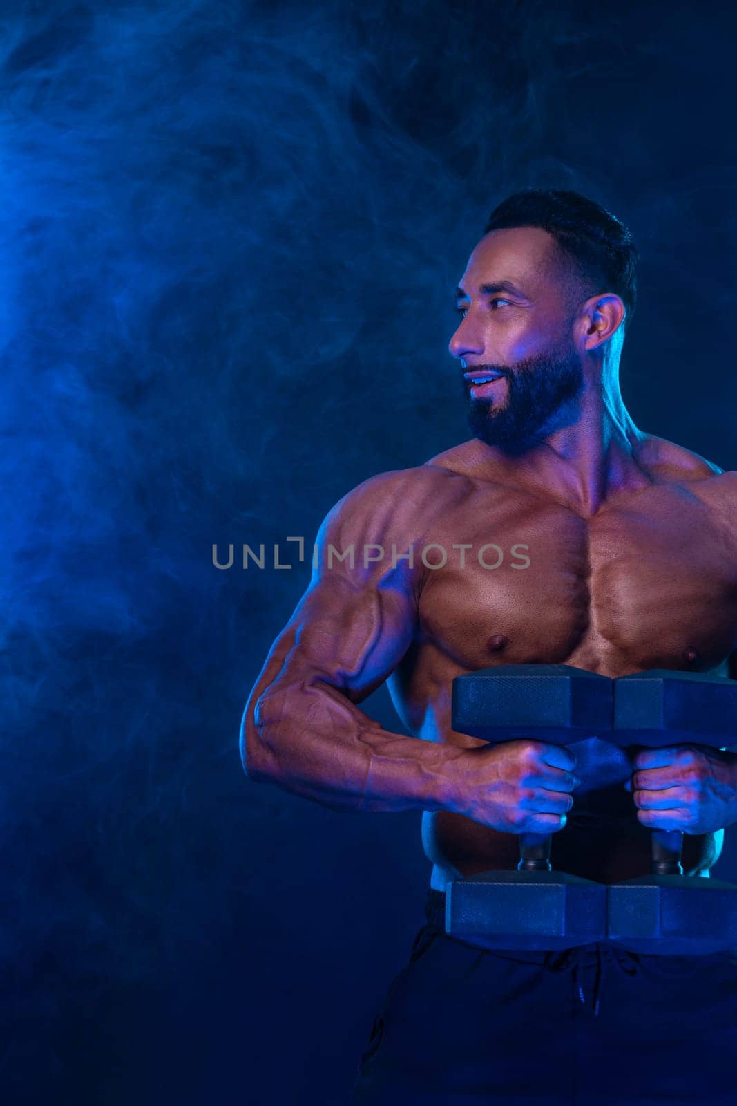 Athlete bodybuilder in neon colors. Fit man posing on black background. Sports concept. Bodybuilding competition. Download, high resolution, photo