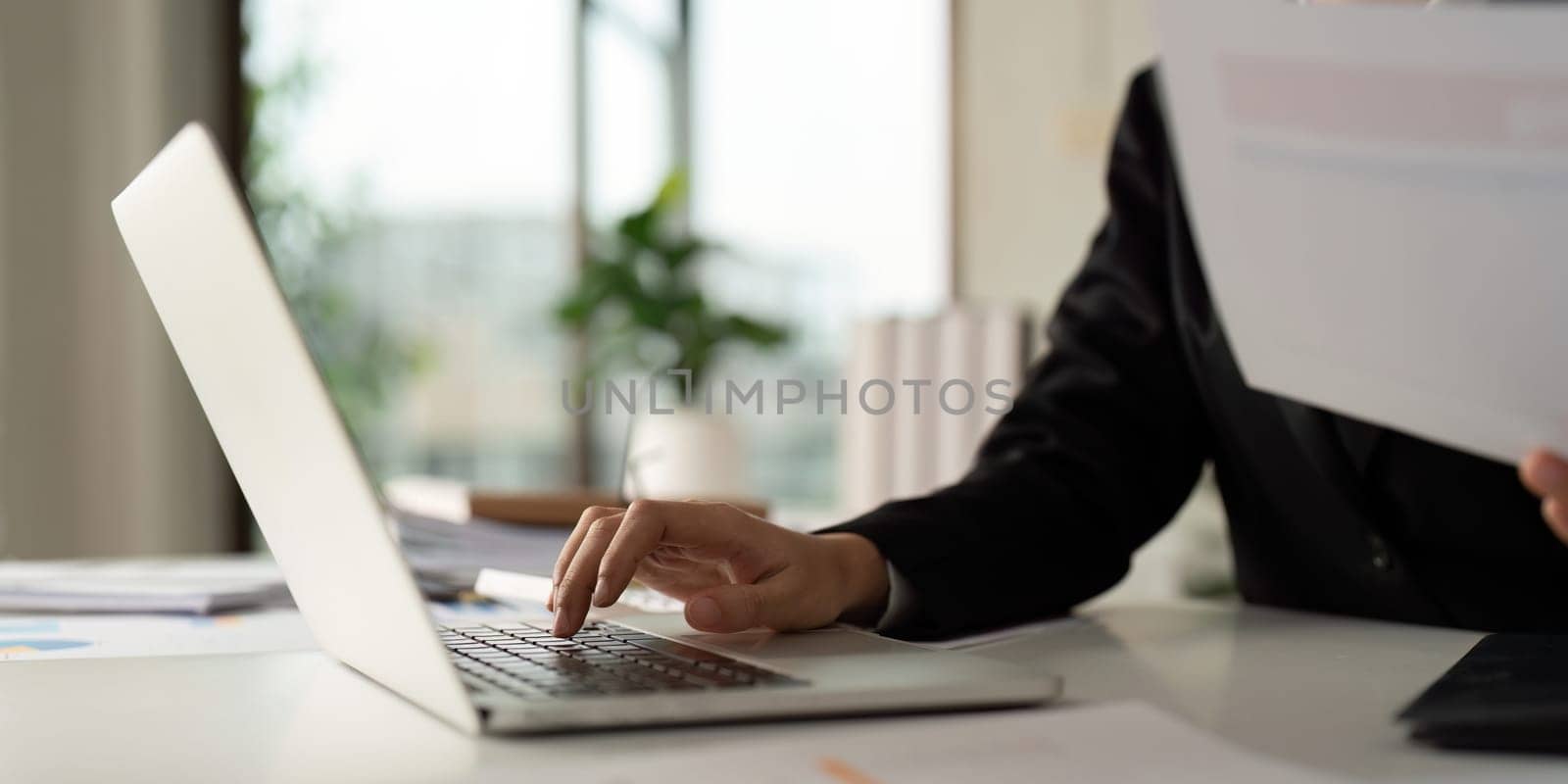 Business woman typing on laptop computer, searching and surfing the internet on office desk.