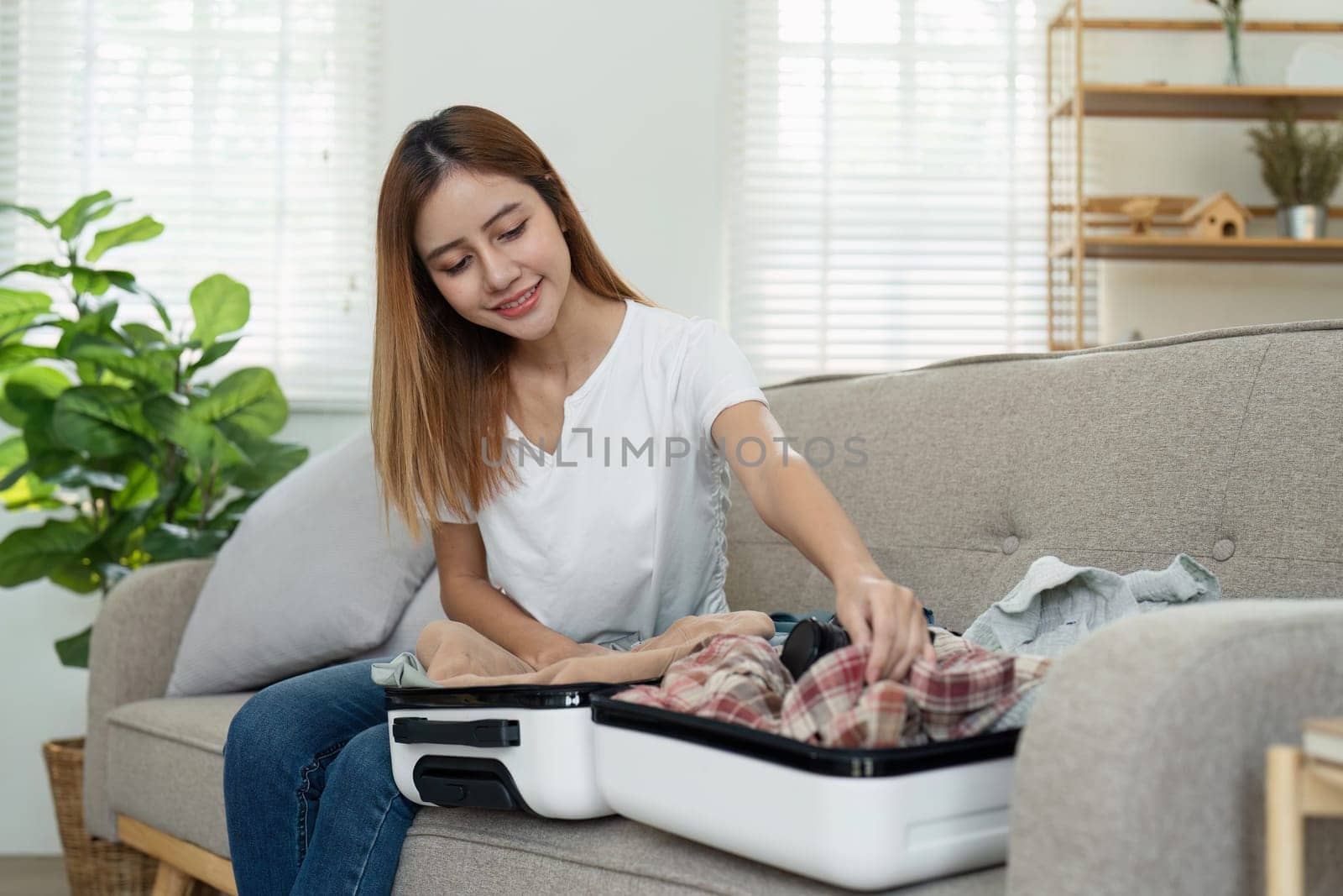Young woman traveler packing suitcase preparing for travel on summer vacation.