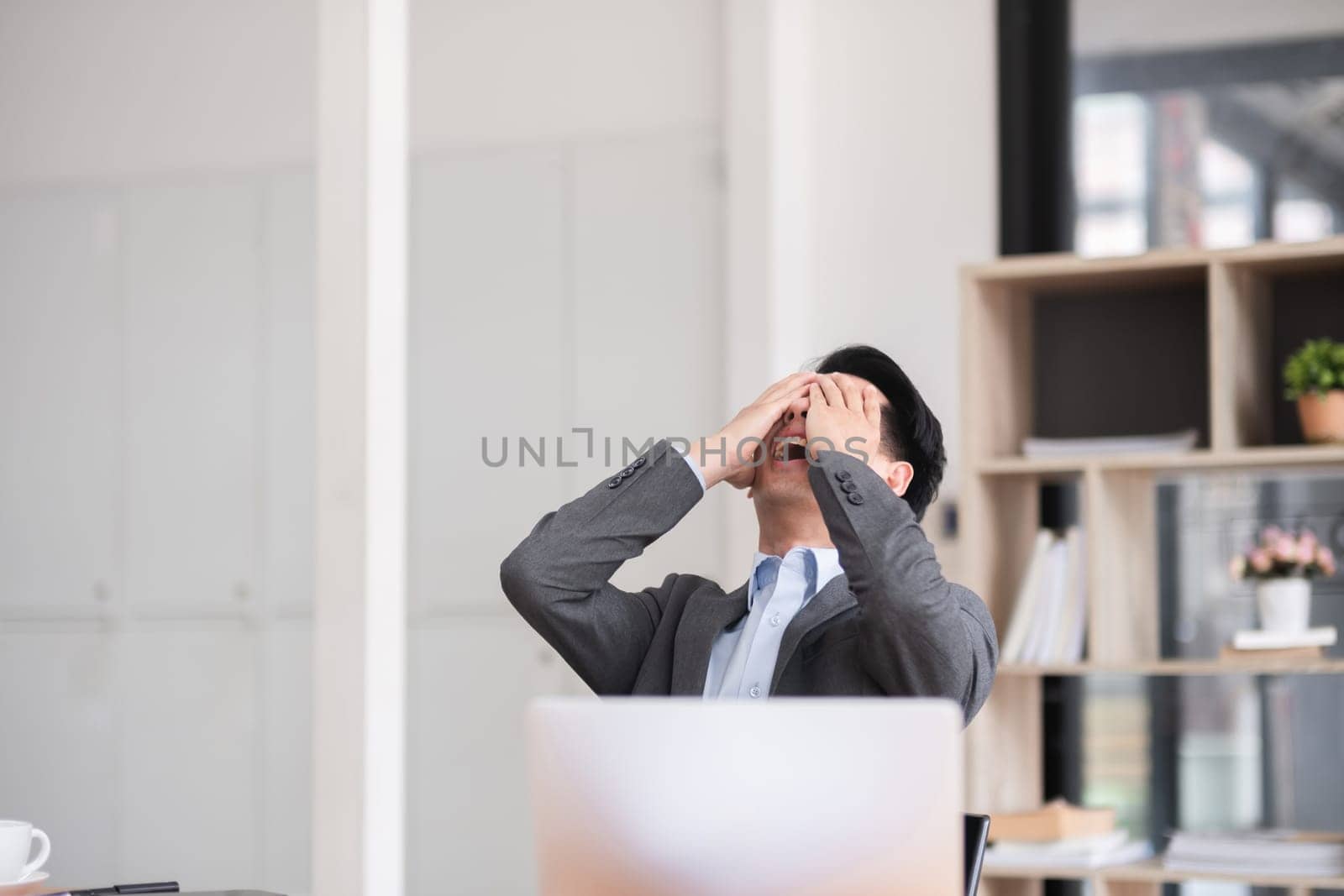 Unhappy young businessman feeling bored or disappointed while sitting in the office Distracted male employee feeling tired from monotonous work.