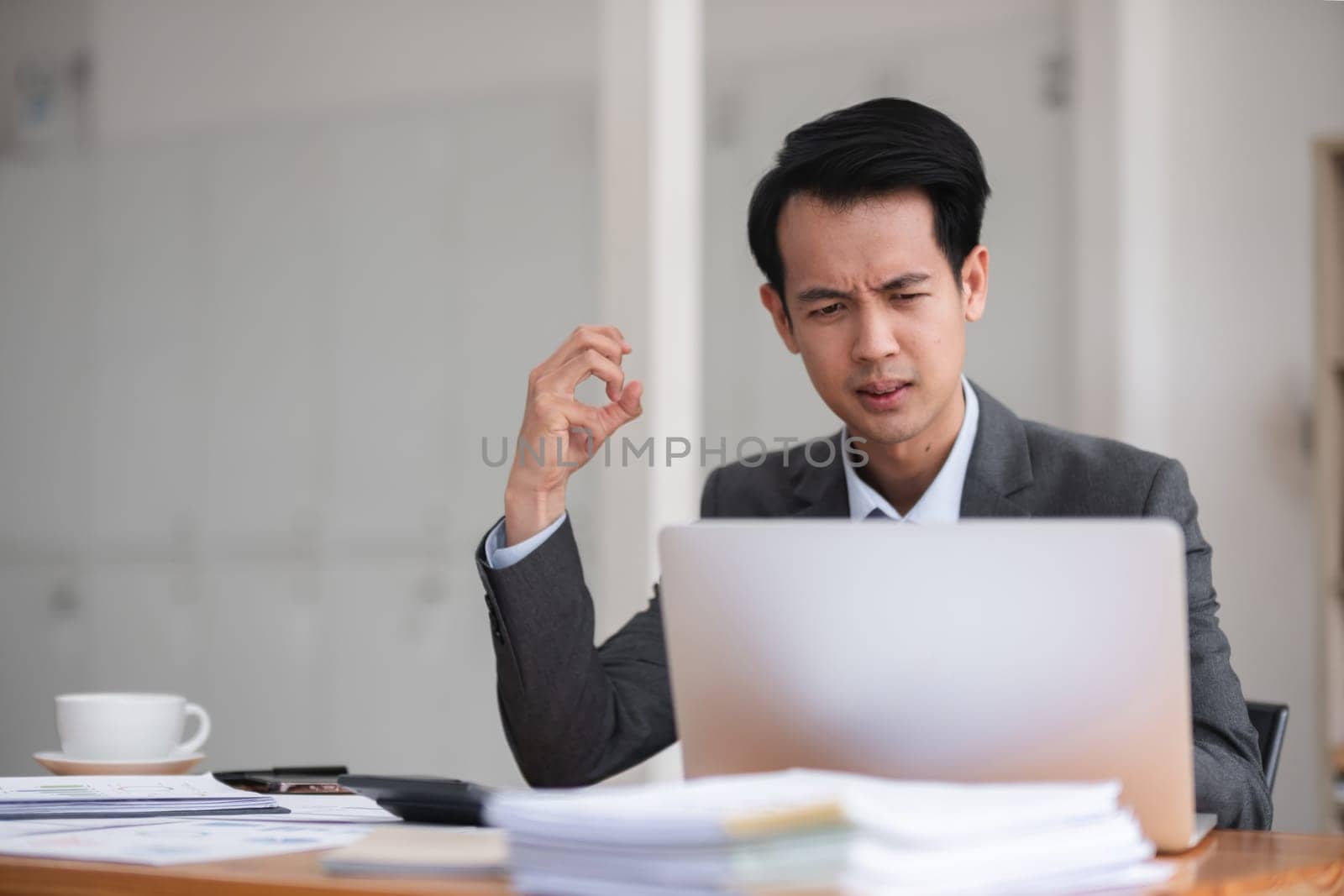 Unhappy young businessman feeling bored or disappointed while sitting in the office Distracted male employee feeling tired from monotonous work.