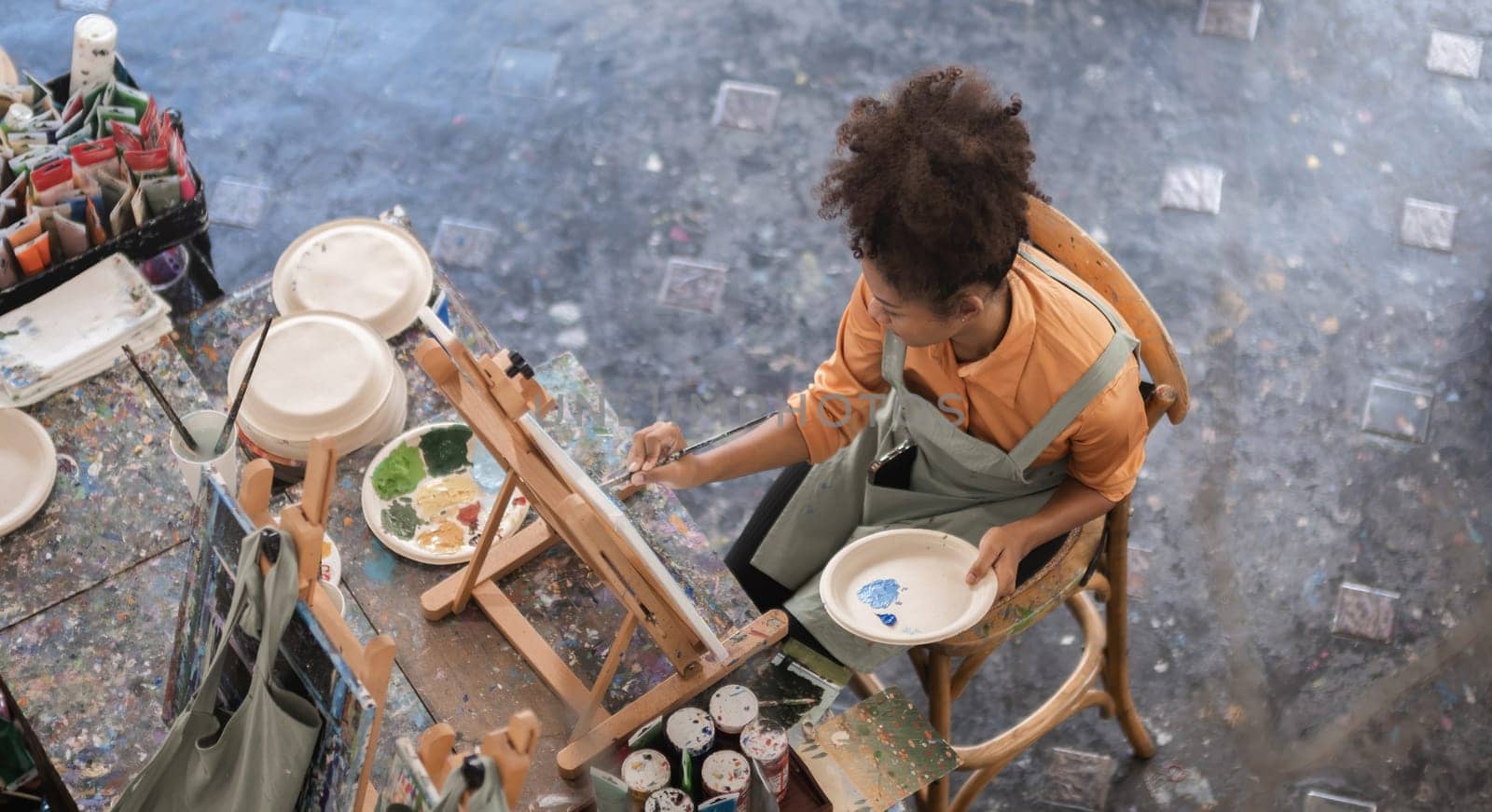 A young black artist paints acrylic paints on canvas with determination in her painting studio by wichayada