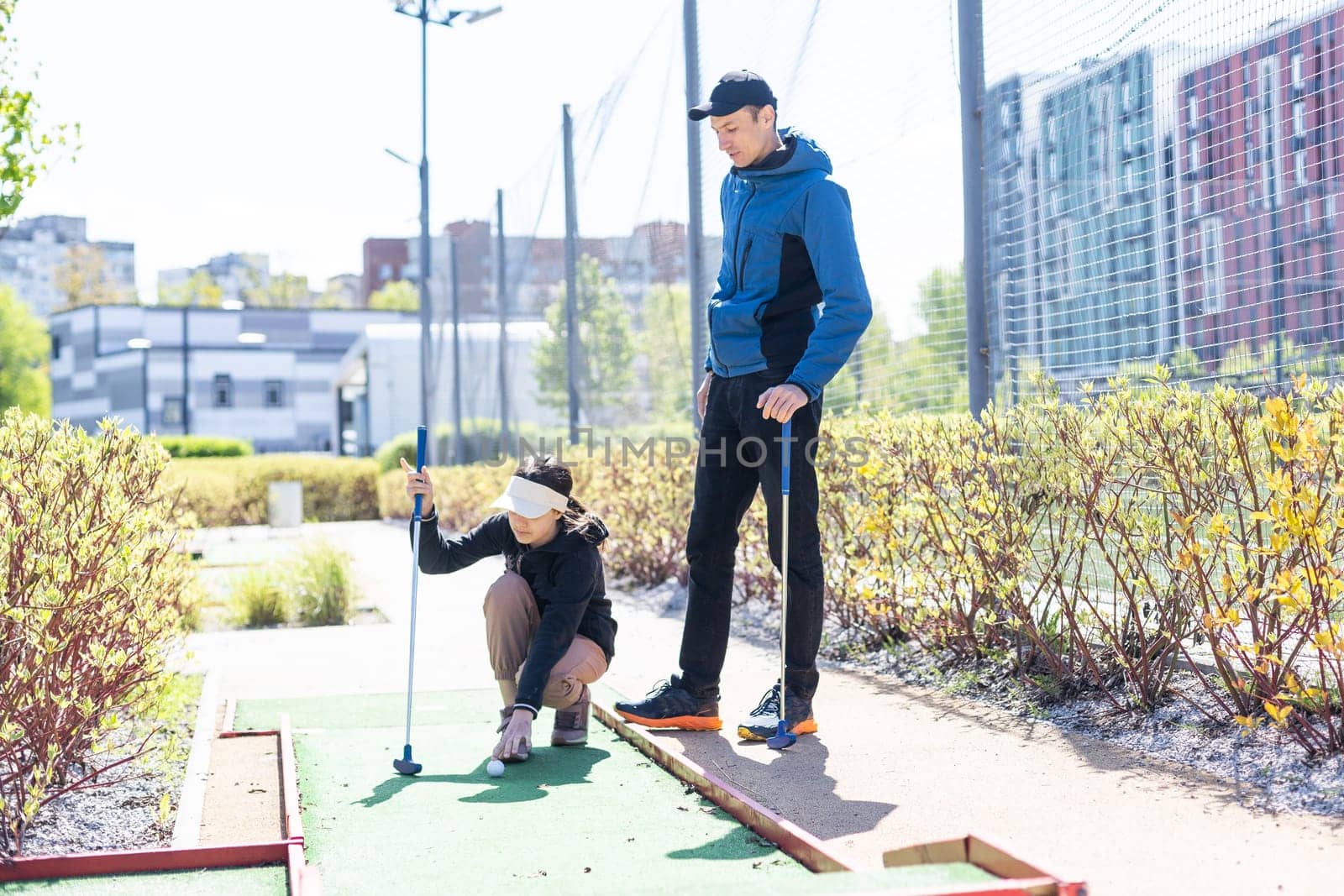 young handsome father teaching his little daughter how to play golf. High quality photo
